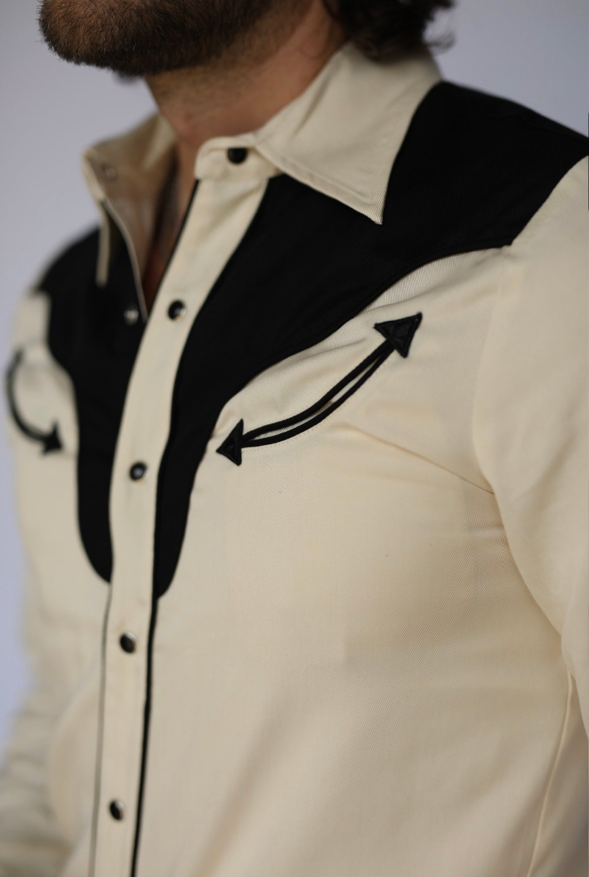 Close-up of the black yoke and embroidered arrow on the H Bar C San Juan off-white western shirt.