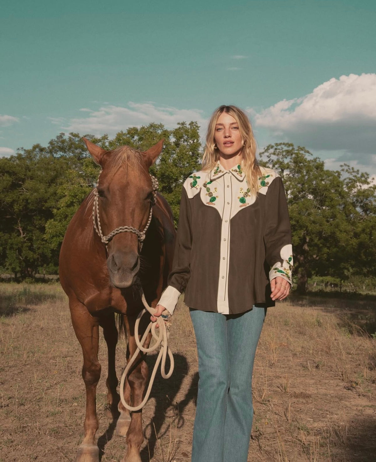 Woman leading a horse in a field wearing the H Bar C San Jose green cactus embroidered western shirt.