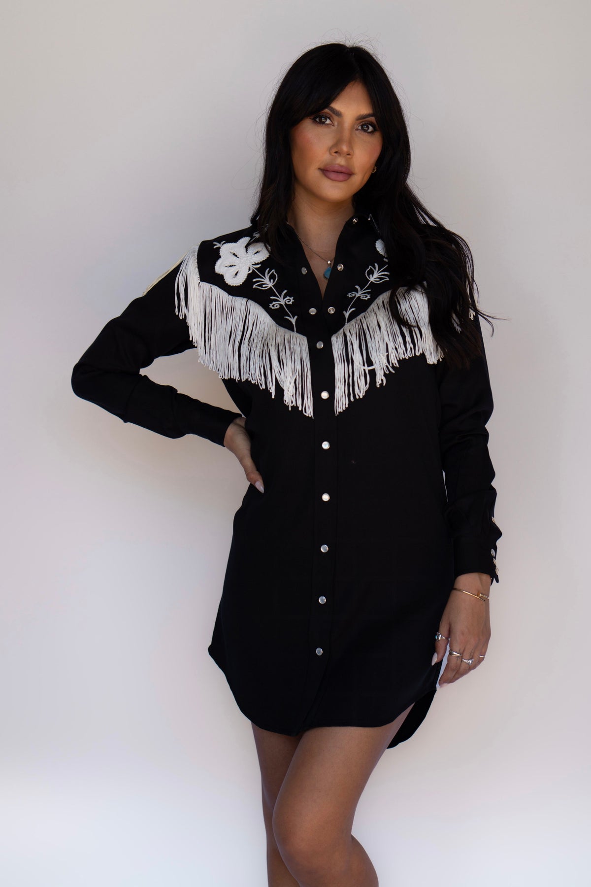 Three-quarter view of the H Bar C Roswell black dress with white fringe across the yoke.