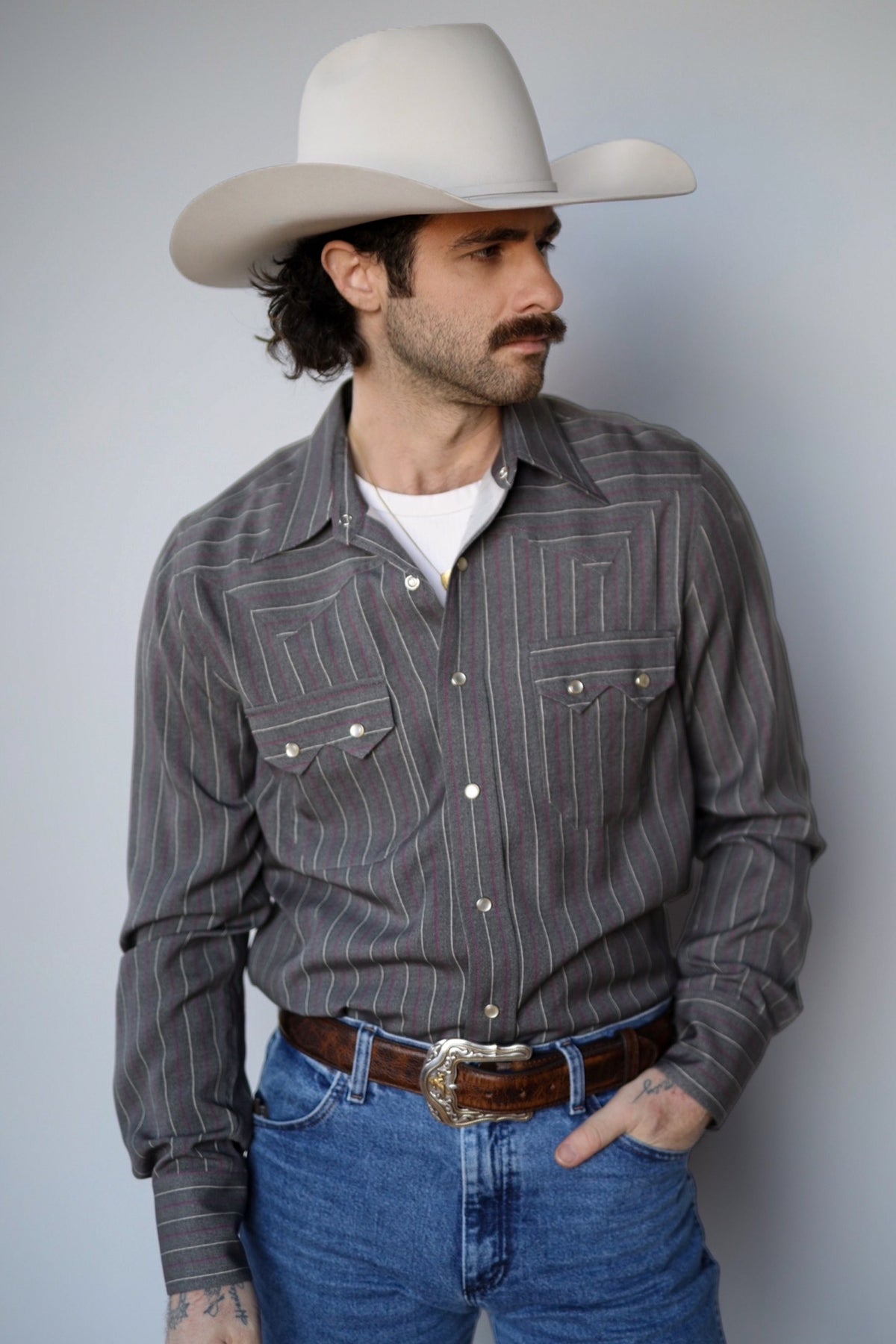 Man in a cream cowboy hat wearing the H Bar C Tiger striped western shirt with jeans.