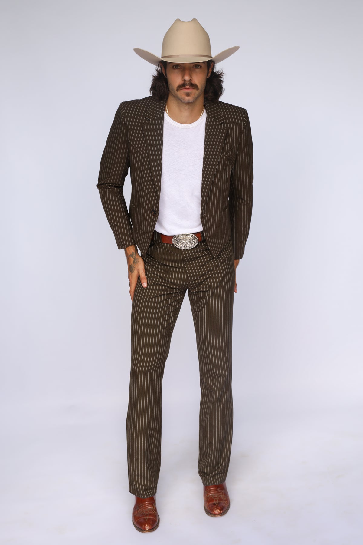 Man wearing the H Bar C Bakersfield jacket in brown pinstripe with matching pants and a cream cowboy hat, a western suit based on a vintage H Bar C design.