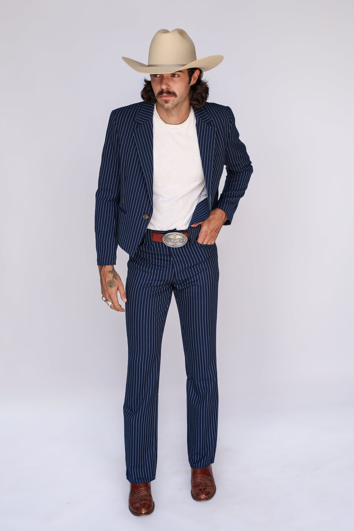 Man wearing the H Bar C Bakersfield navy pin stripe jacket open over a white tee with matching pants, boots, and cowboy hat.