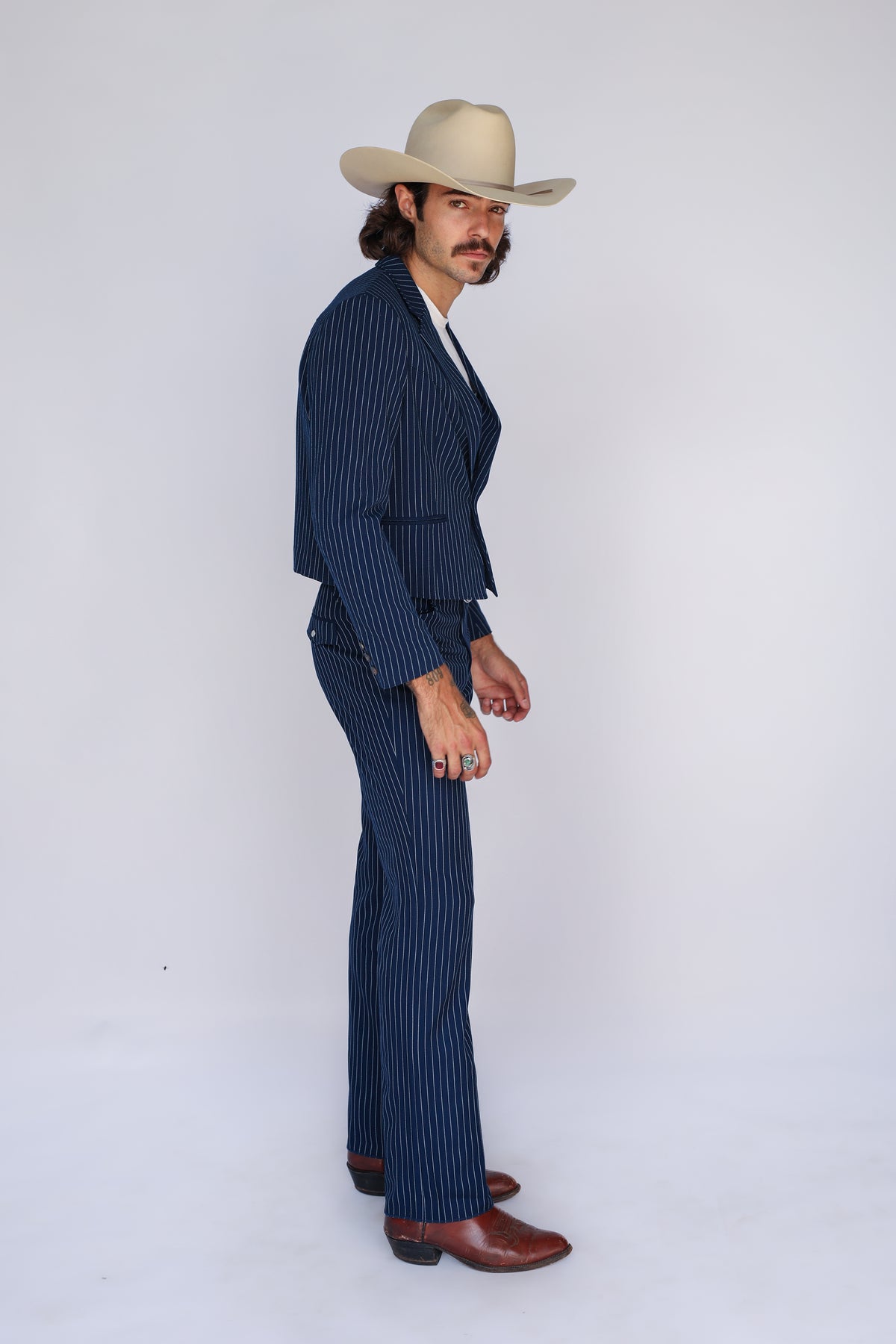 Side view of a man in a cowboy hat wearing the H Bar C Bakersfield navy pinstripe western suit.