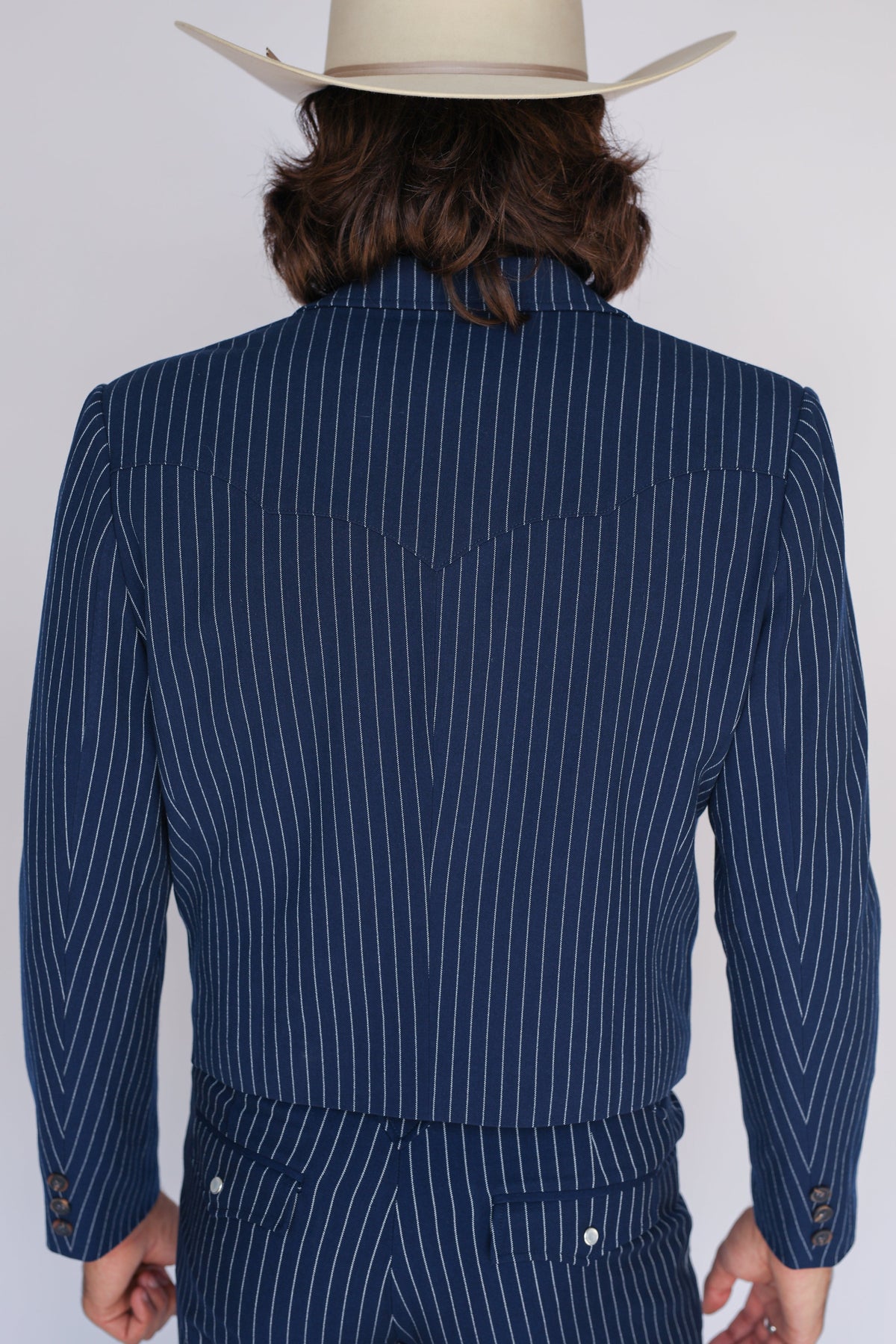 Back shoulder view of the H Bar C Bakersfield navy pin stripe jacket with a cream cowboy hat.