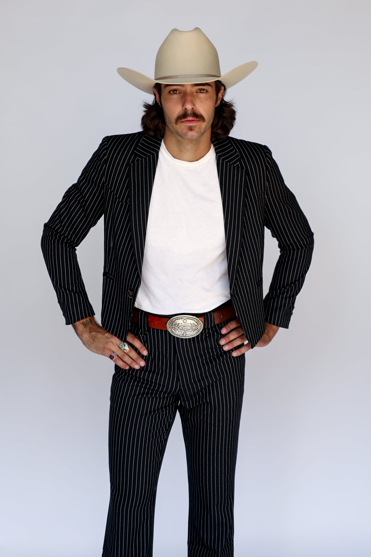 Man wearing the H Bar C Bakersfield jacket in black pinstripe with matching pants and a cream cowboy hat, a western suit from a vintage H Bar C design.