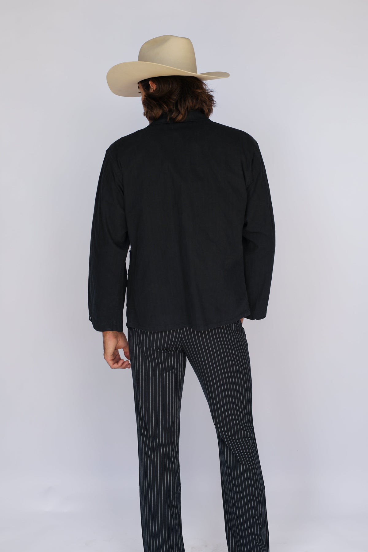 Back view of the H Bar C Normandy black chore coat with a cowboy hat.