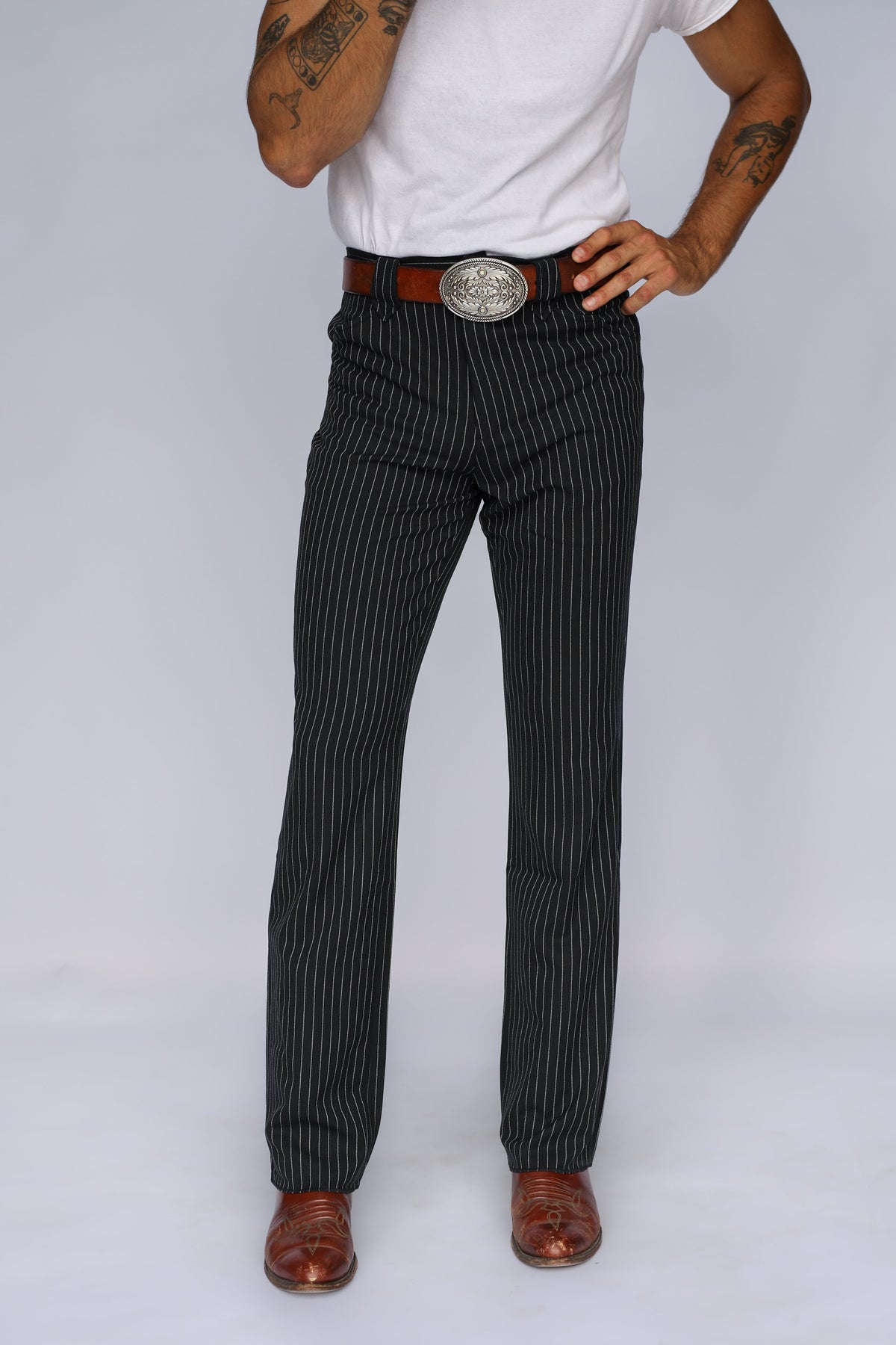 Front view of the H Bar C Bakersfield western pants in black pinstripe with a silver buckle and brown boots.