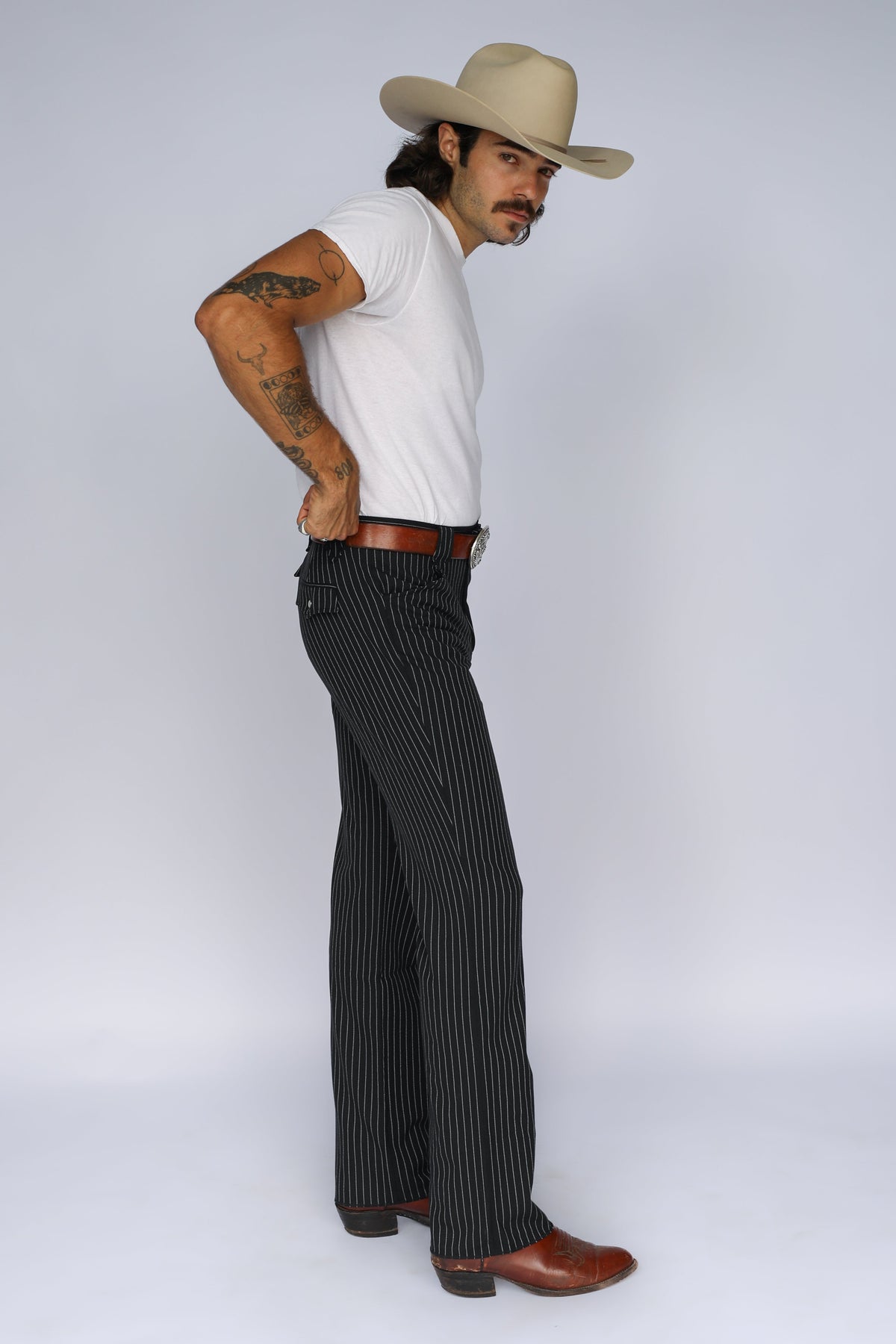 Side view of a man in a cowboy hat wearing the H Bar C Bakersfield black pinstripe western pants.