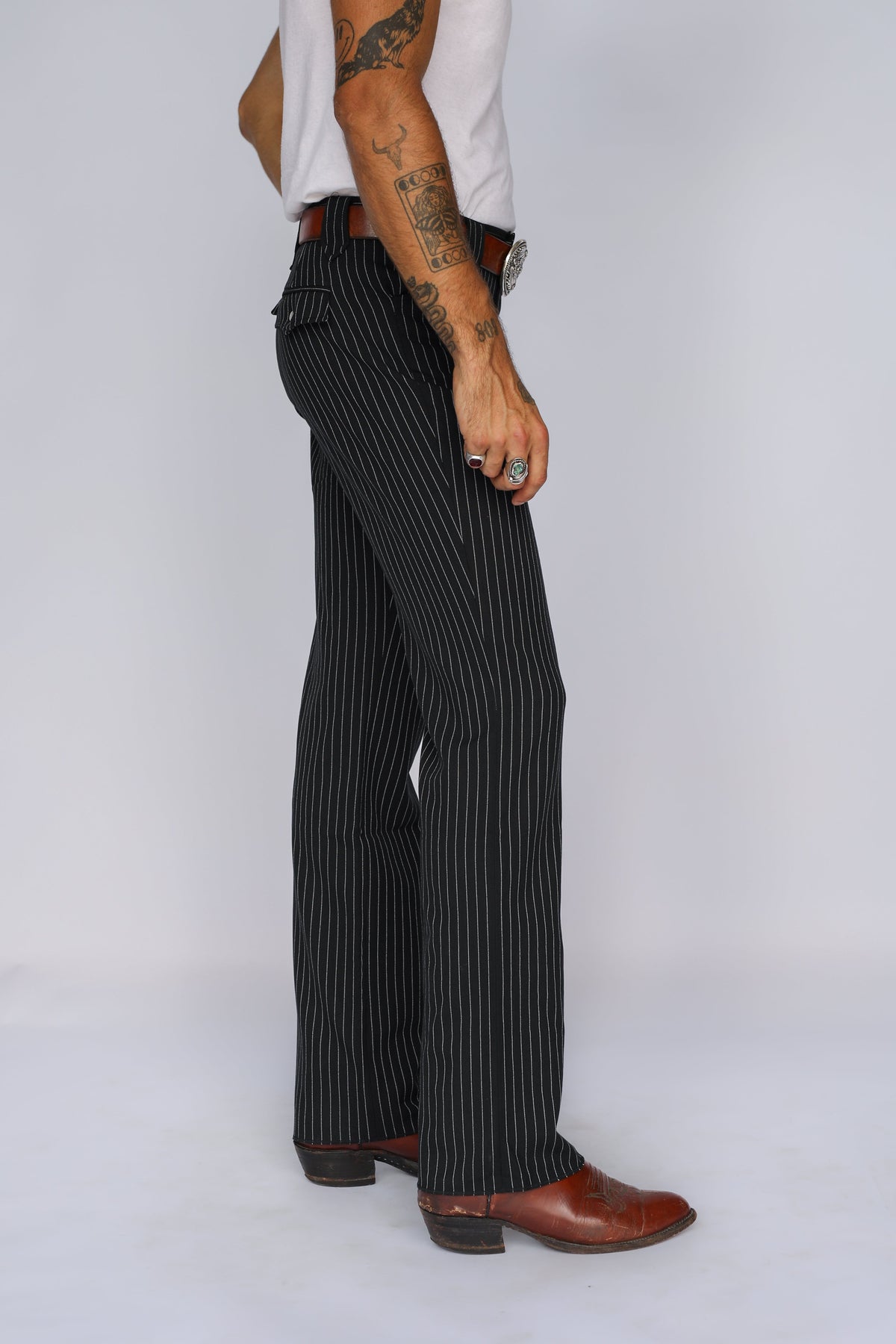 Side profile of the H Bar C Bakersfield black pinstripe pants with straight leg over cowboy boots.