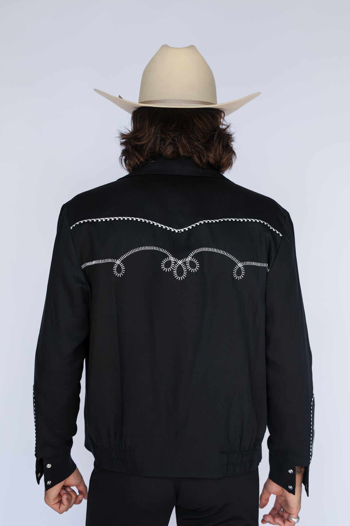 Close-up of the white chain stitch scrollwork on the back yoke of the H Bar C Bolero men's black western jacket.