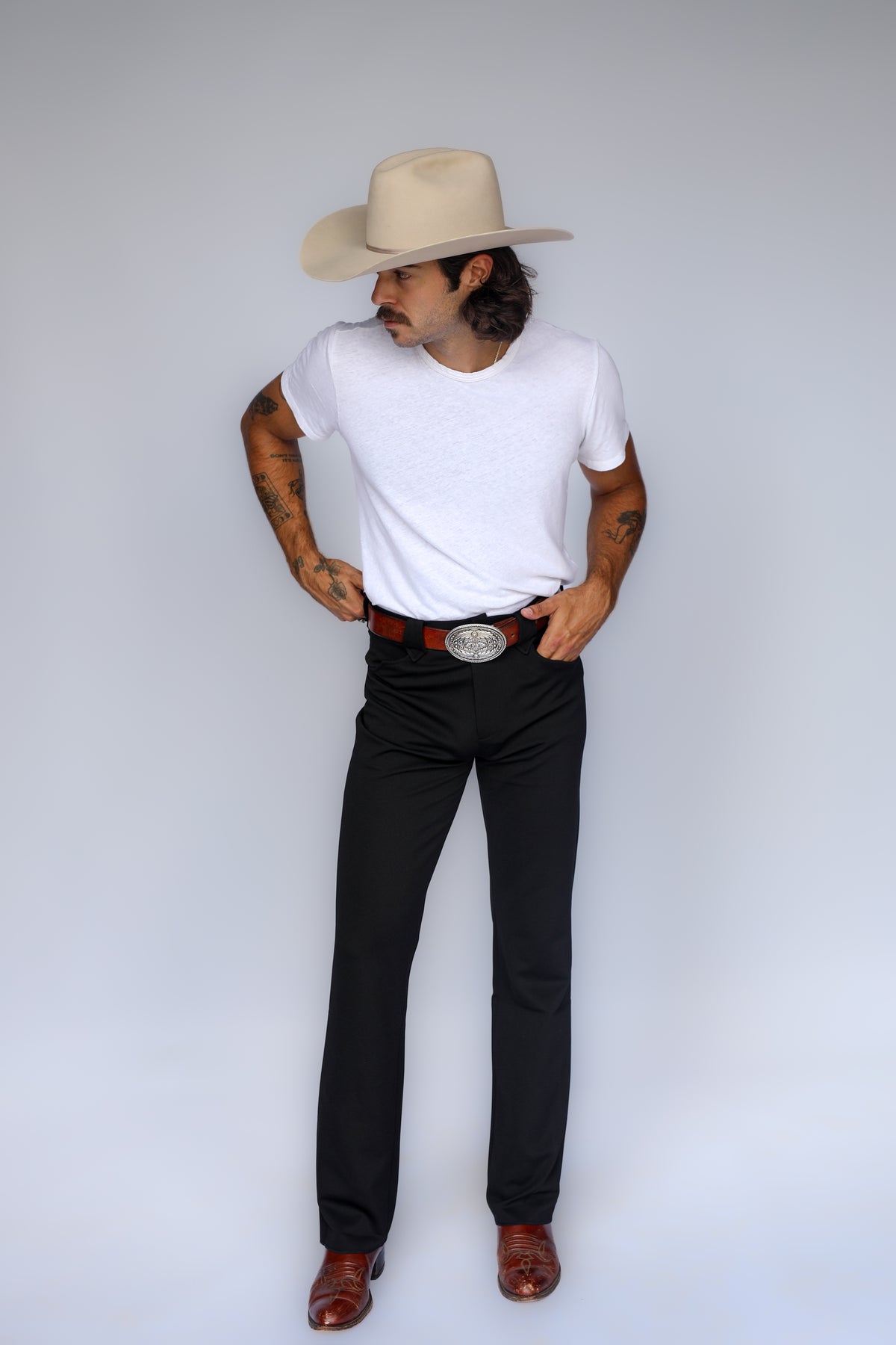 Full length view of a man in a cowboy hat wearing the H Bar C Franklin black western pants with a white tee and brown boots.