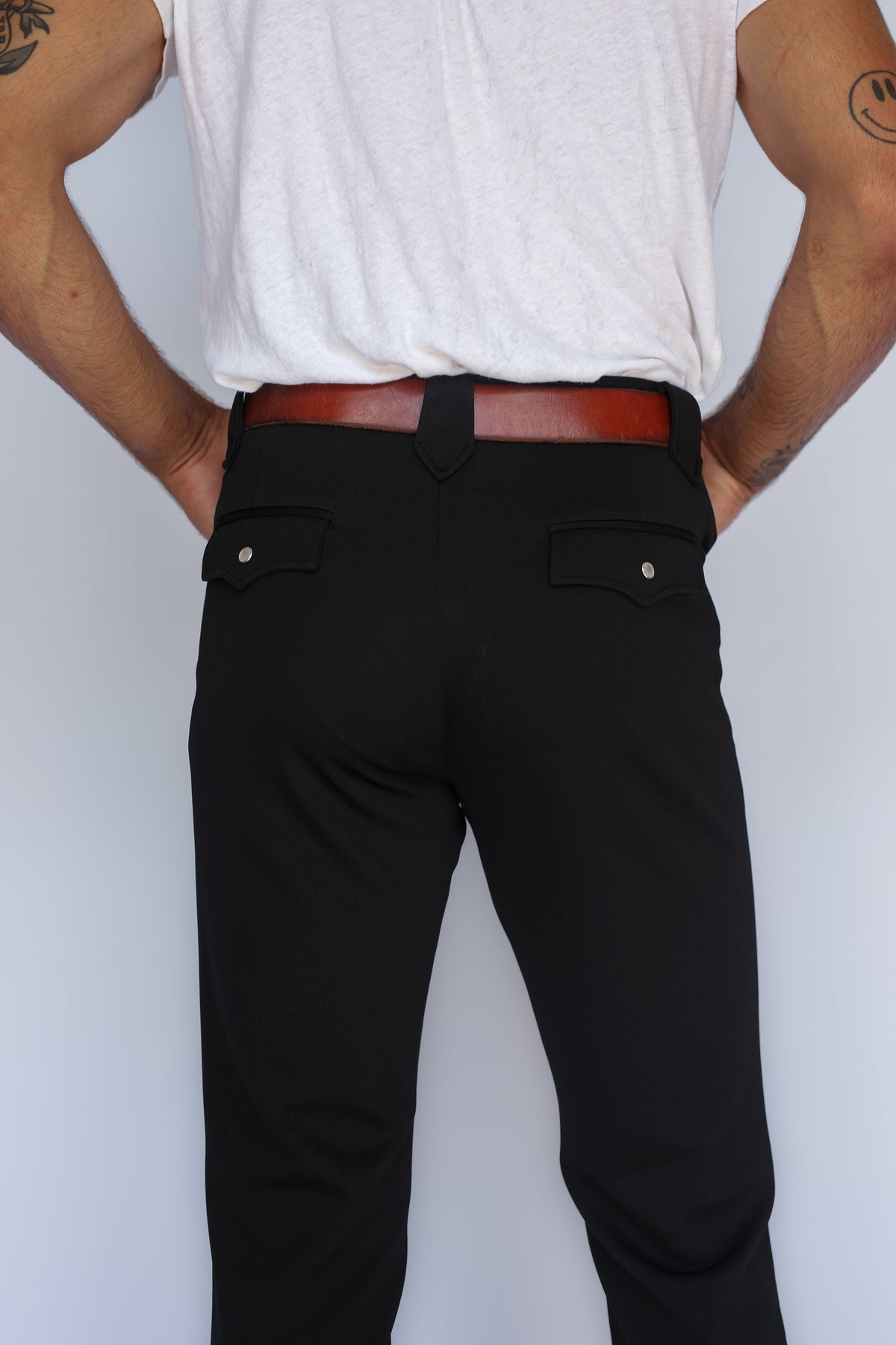 Back pocket and waistband detail of the H Bar C Bolero black western pants worn with a brown leather belt.