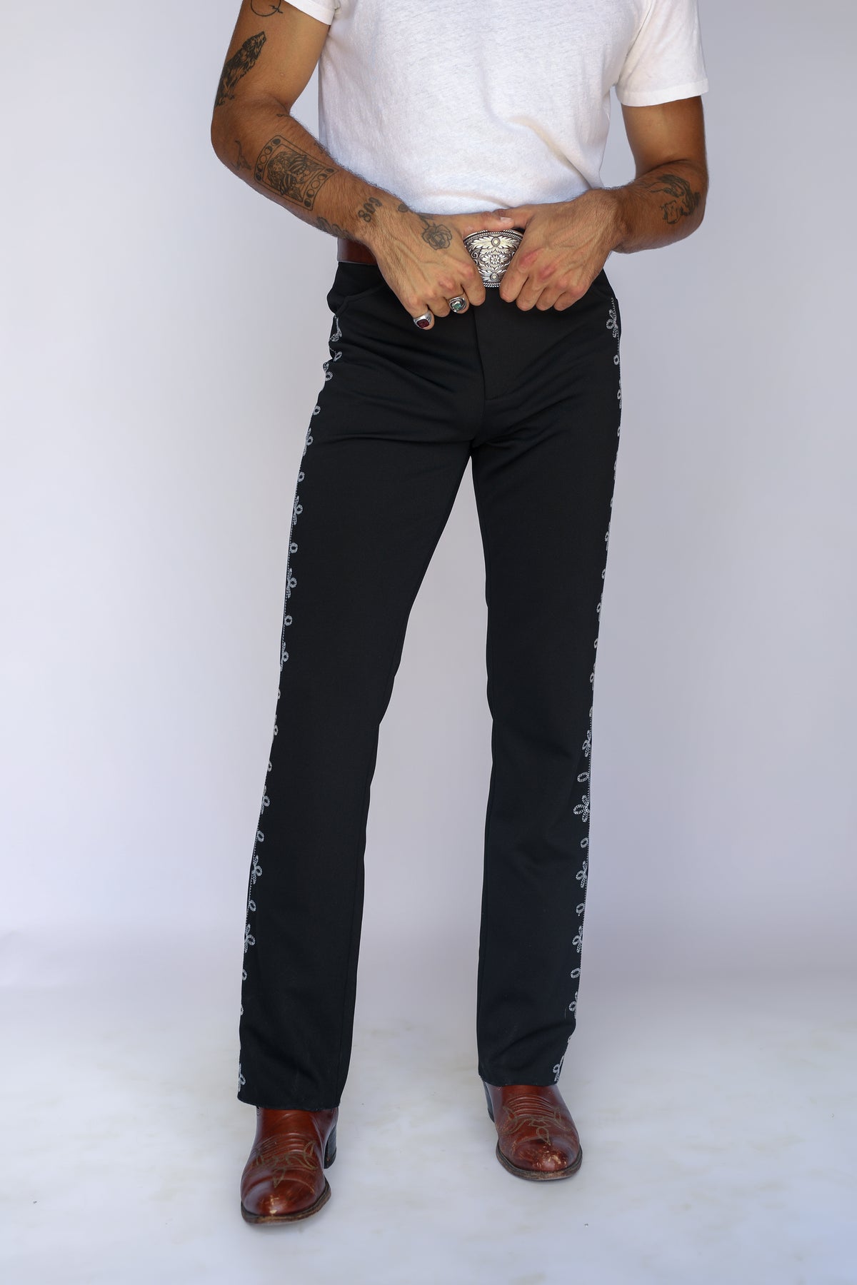 Front view of the H Bar C Bolero black pants with embroidered side stripe, worn with a white tee and silver buckle.