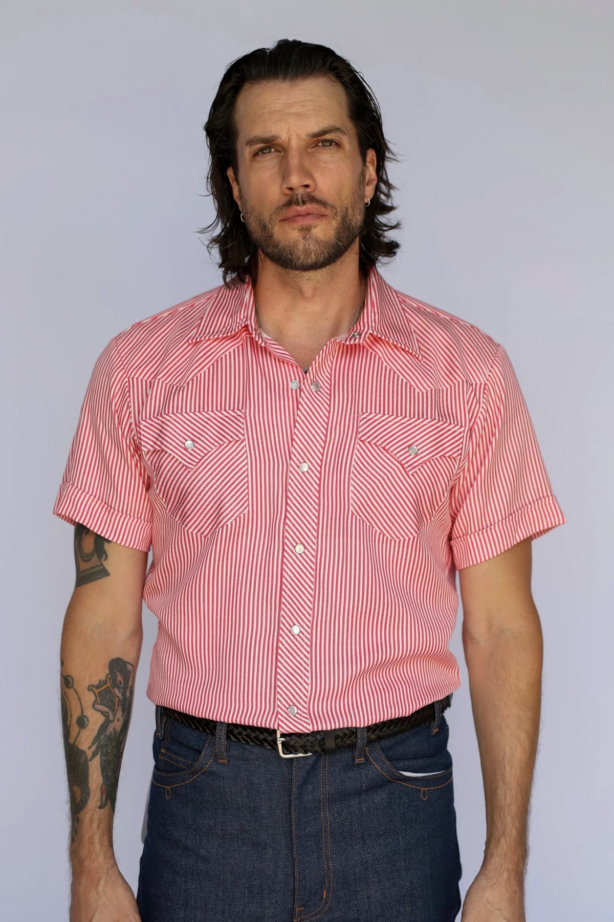 Man wearing the H Bar C Newport short sleeve western shirt in red stripe with pearl snaps, tucked into dark jeans.