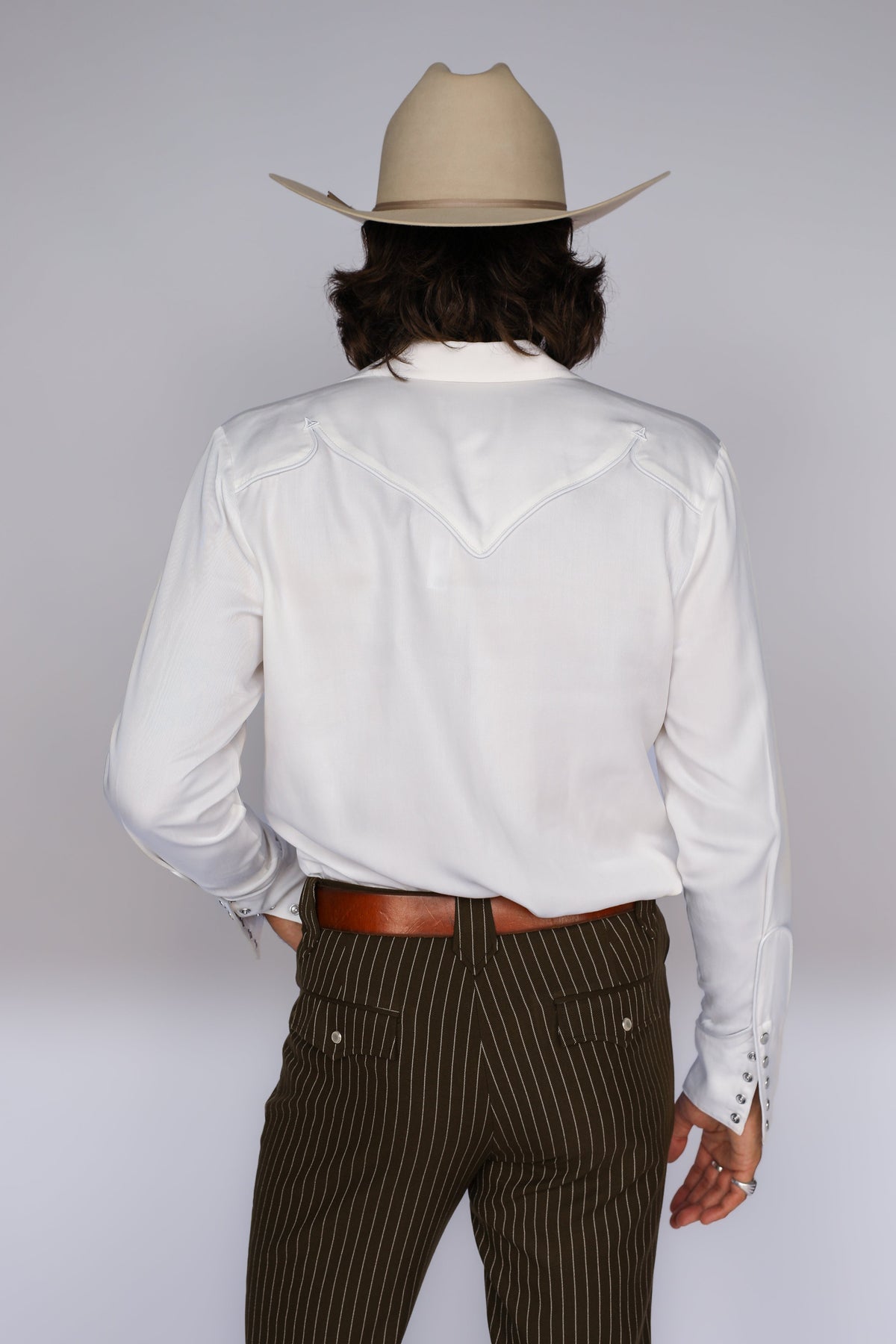 Back view of the H Bar C Reno men's white shirt with western back yoke and a cowboy hat.