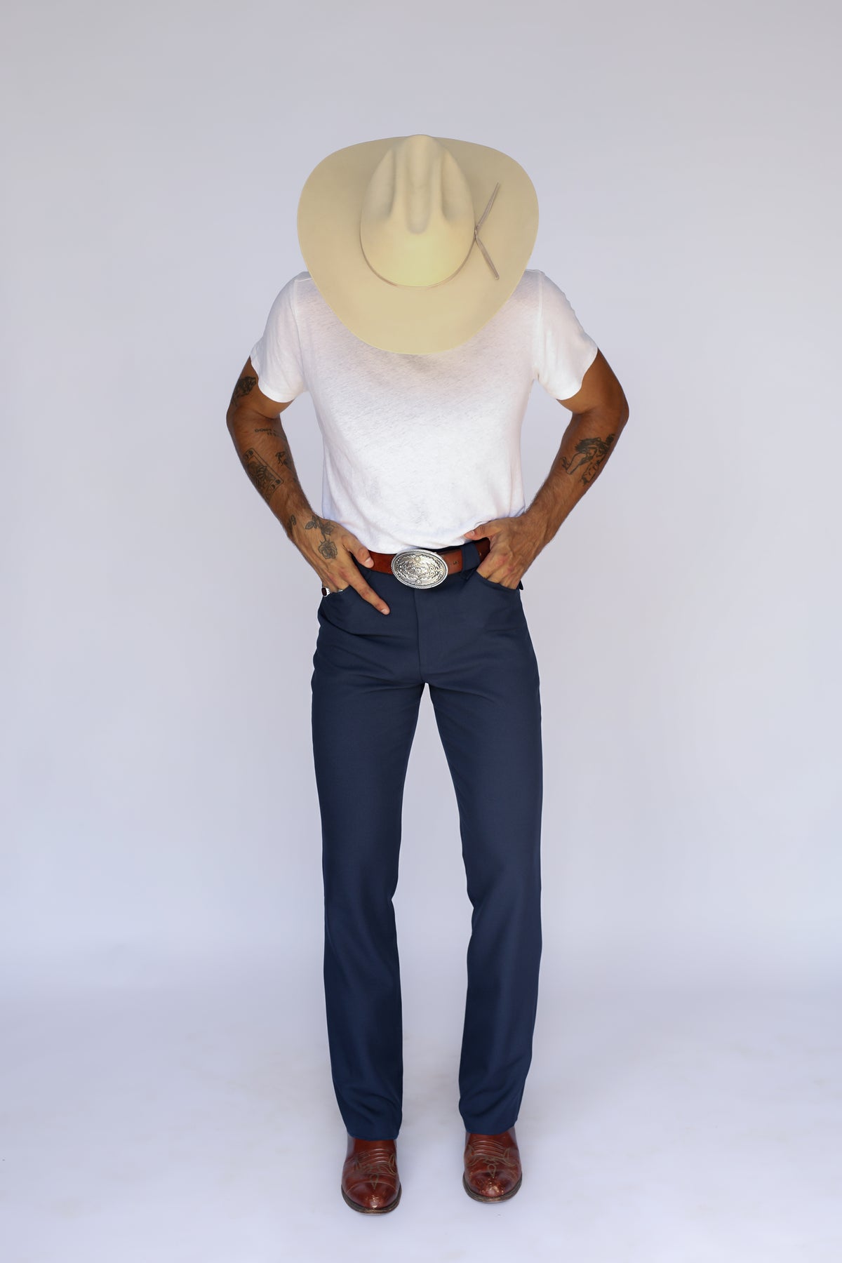 Man in a cowboy hat wearing the H Bar C Franklin navy western pants with a white tee and silver buckle.