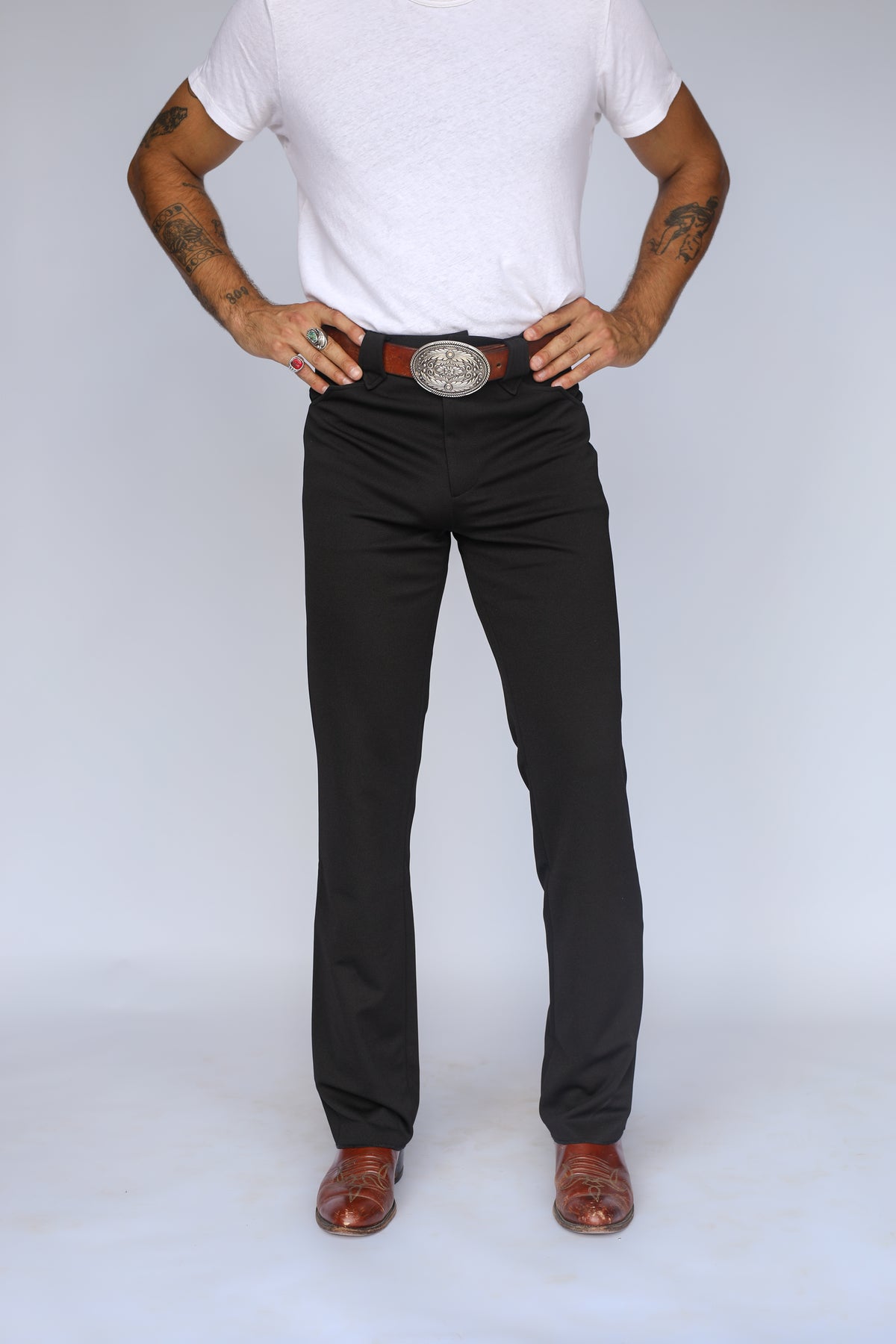 Front view of the H Bar C Franklin unisex western pants in black, a stretch dress pant with a classic western cut, worn with a silver buckle.
