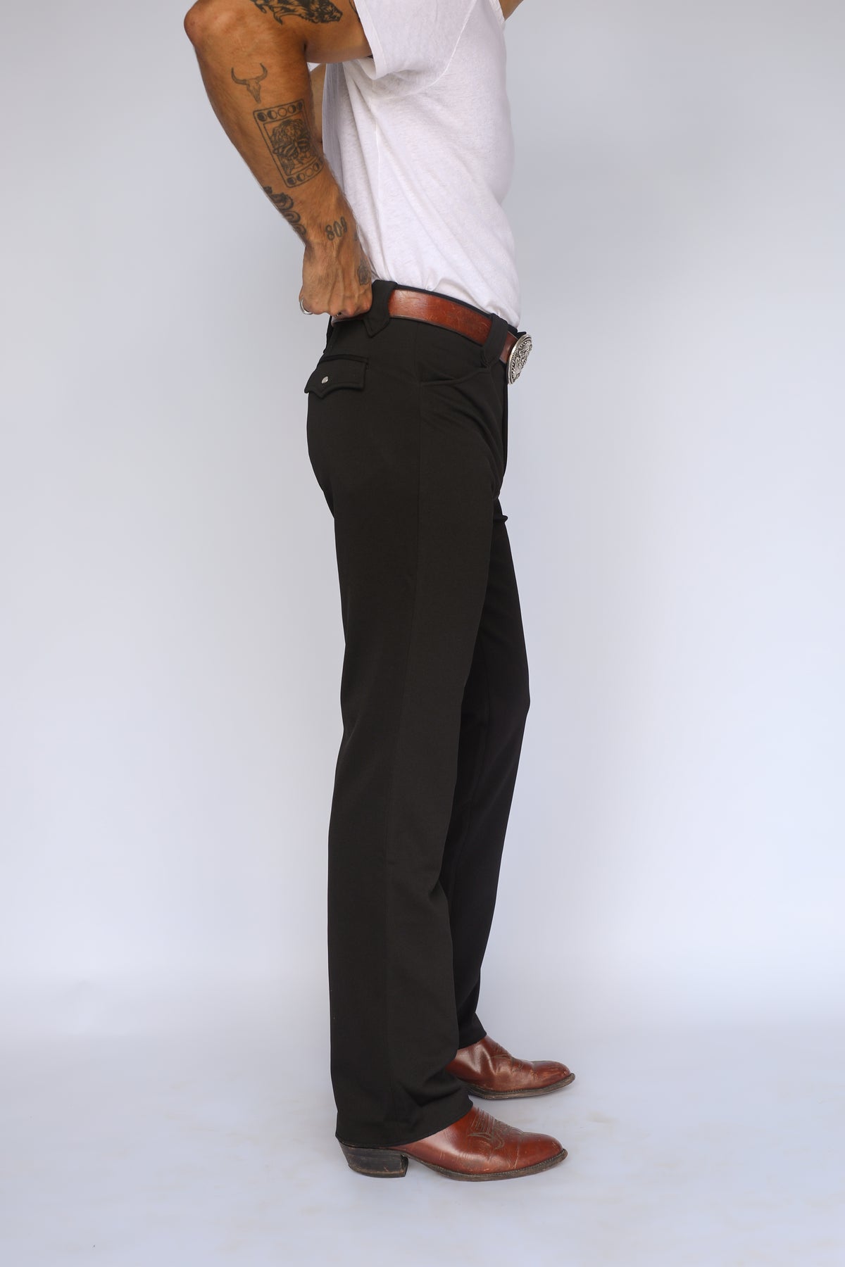 Side profile of the H Bar C Franklin unisex western pants in black with a straight leg over cowboy boots.