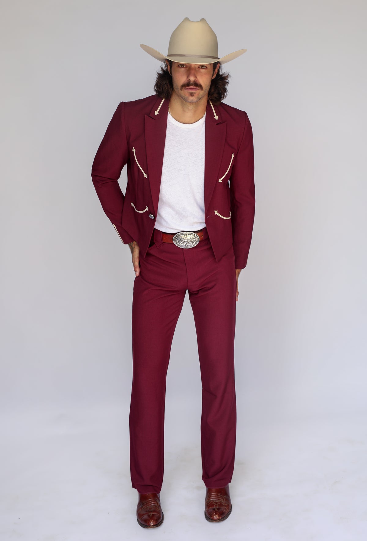Full length view of the H Bar C Calamity men's maroon jacket and matching maroon western pants with a cowboy hat.