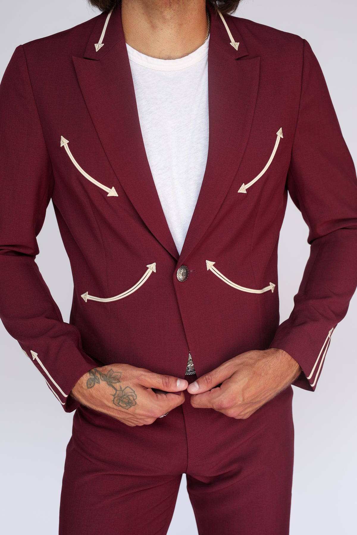 Close-up of the H Bar C Calamity maroon jacket buttoned over a white tee, showing cream arrow smile pockets.