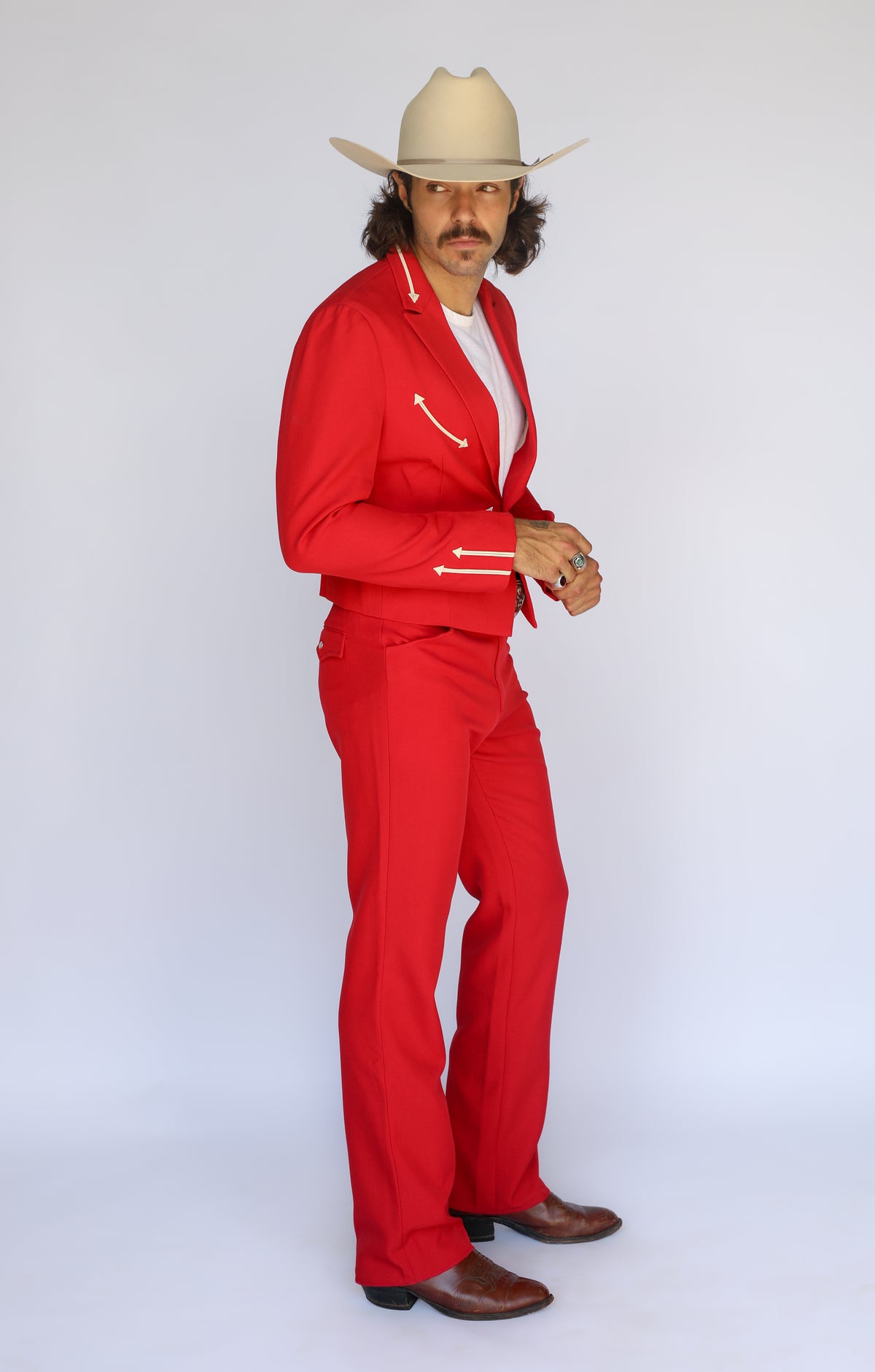 Side profile of the H Bar C Calamity red jacket with cream arrow cuff details and matching pants.