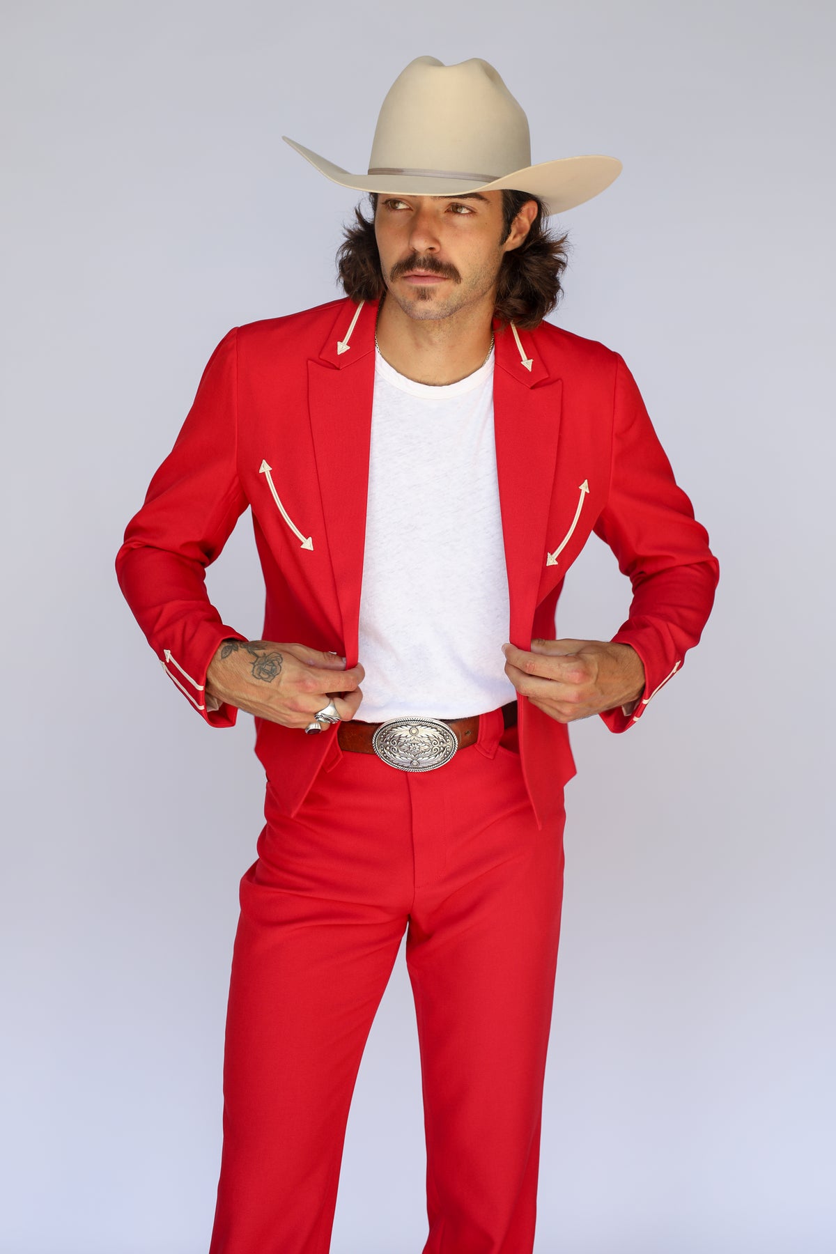 Man buttoning the H Bar C Calamity red western blazer with cream arrow smile pockets.