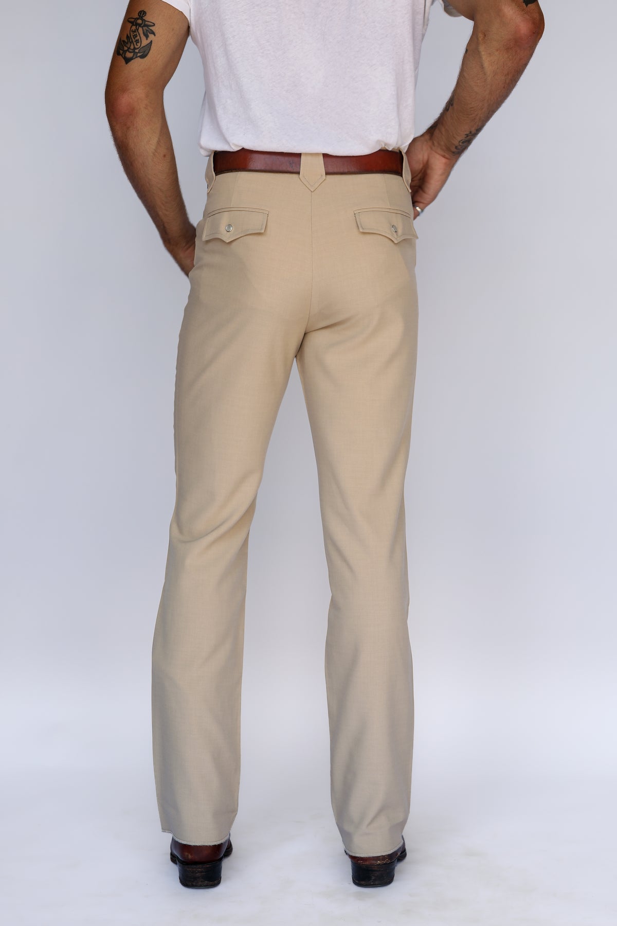Rear view of the H Bar C Calamity unisex tan pants with brown belt and boots.