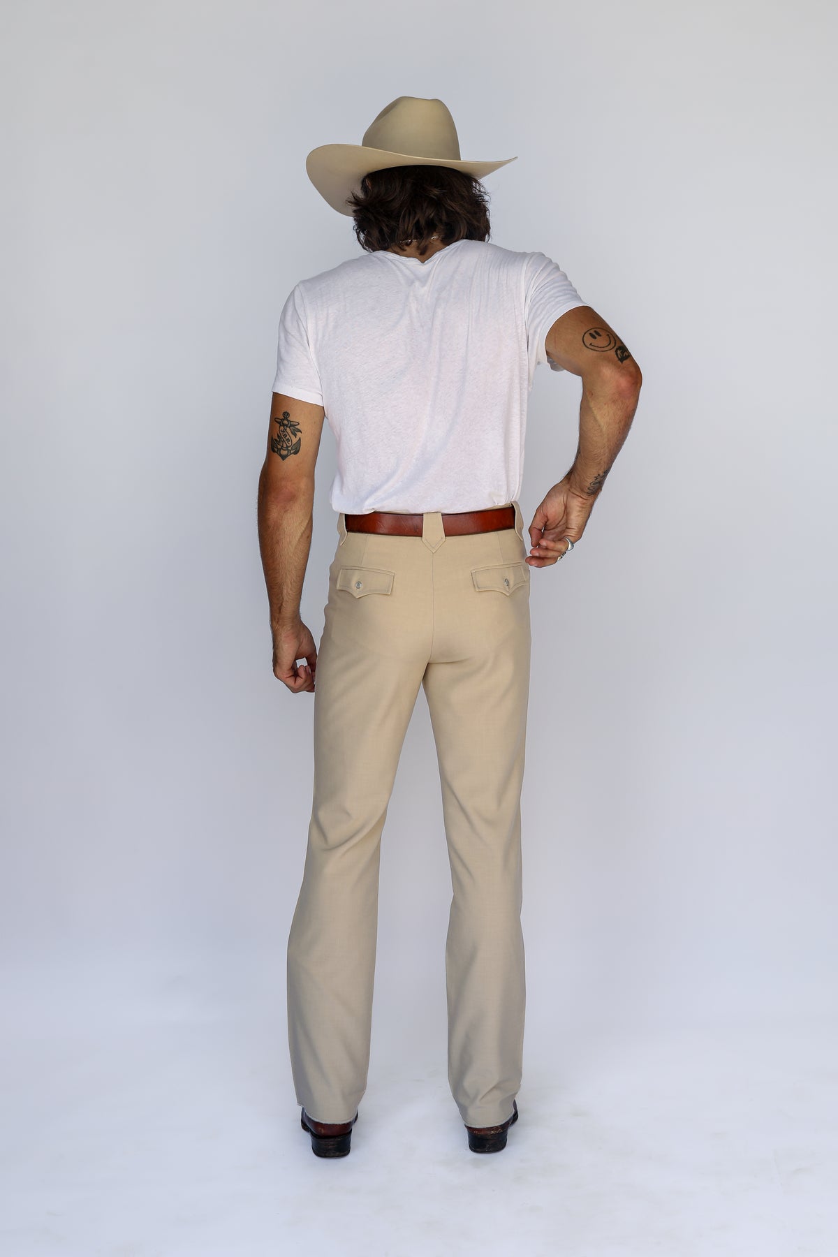 Full back view of a man in a cowboy hat wearing the H Bar C Calamity tan western pants.