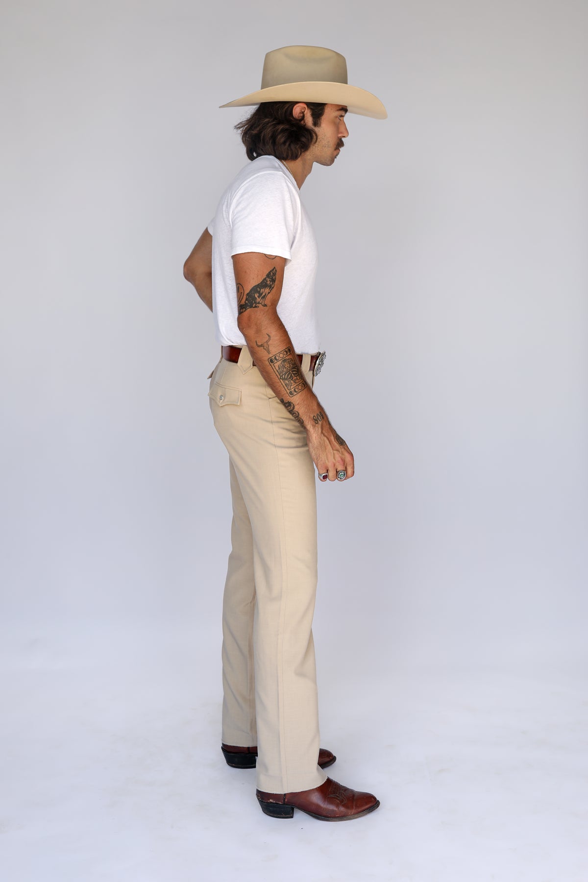 Side view of a man in a cowboy hat wearing the H Bar C Calamity tan western pants.