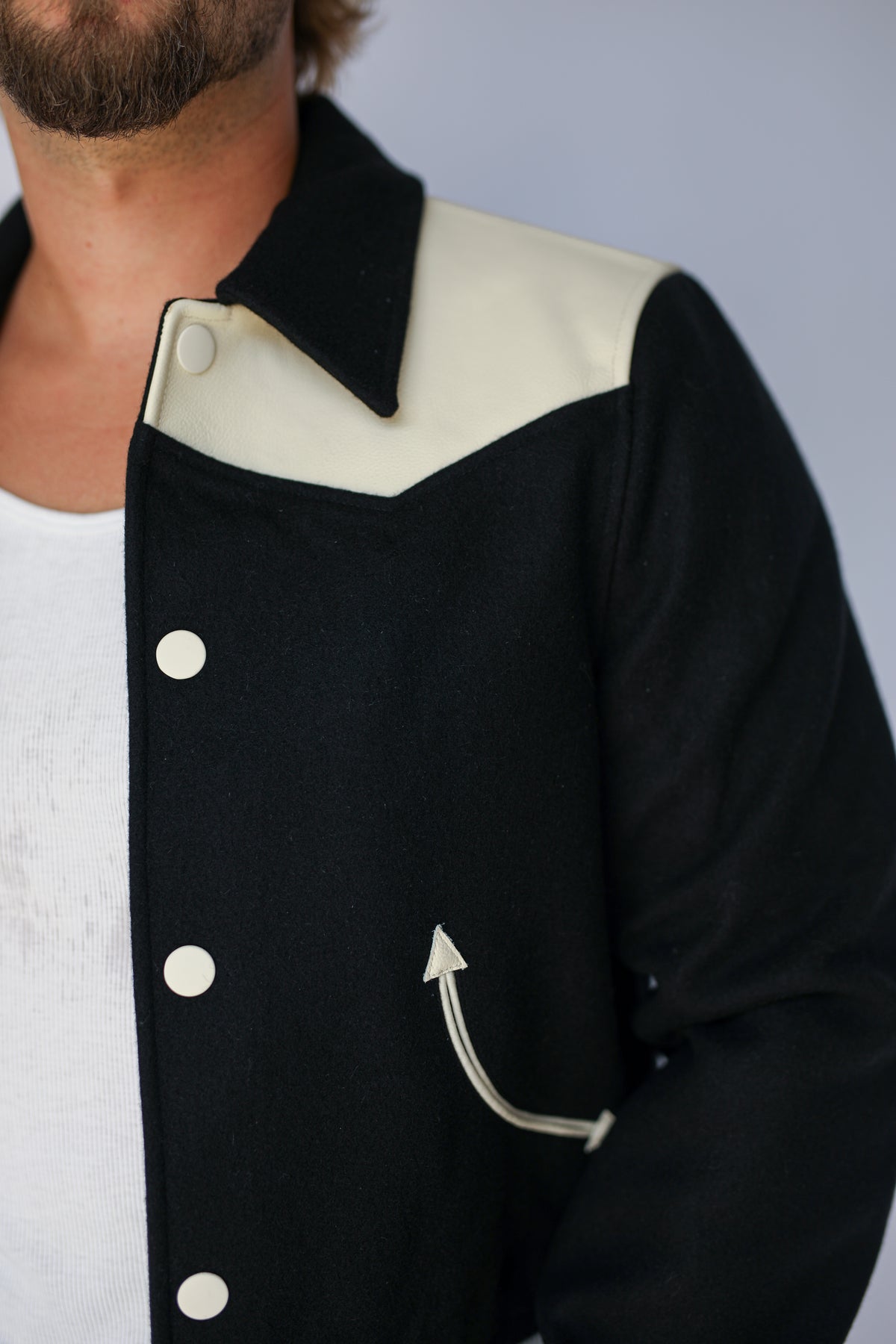 Detail of the cream yoke, collar, and snap front on The Vail unisex black jacket by H Bar C.