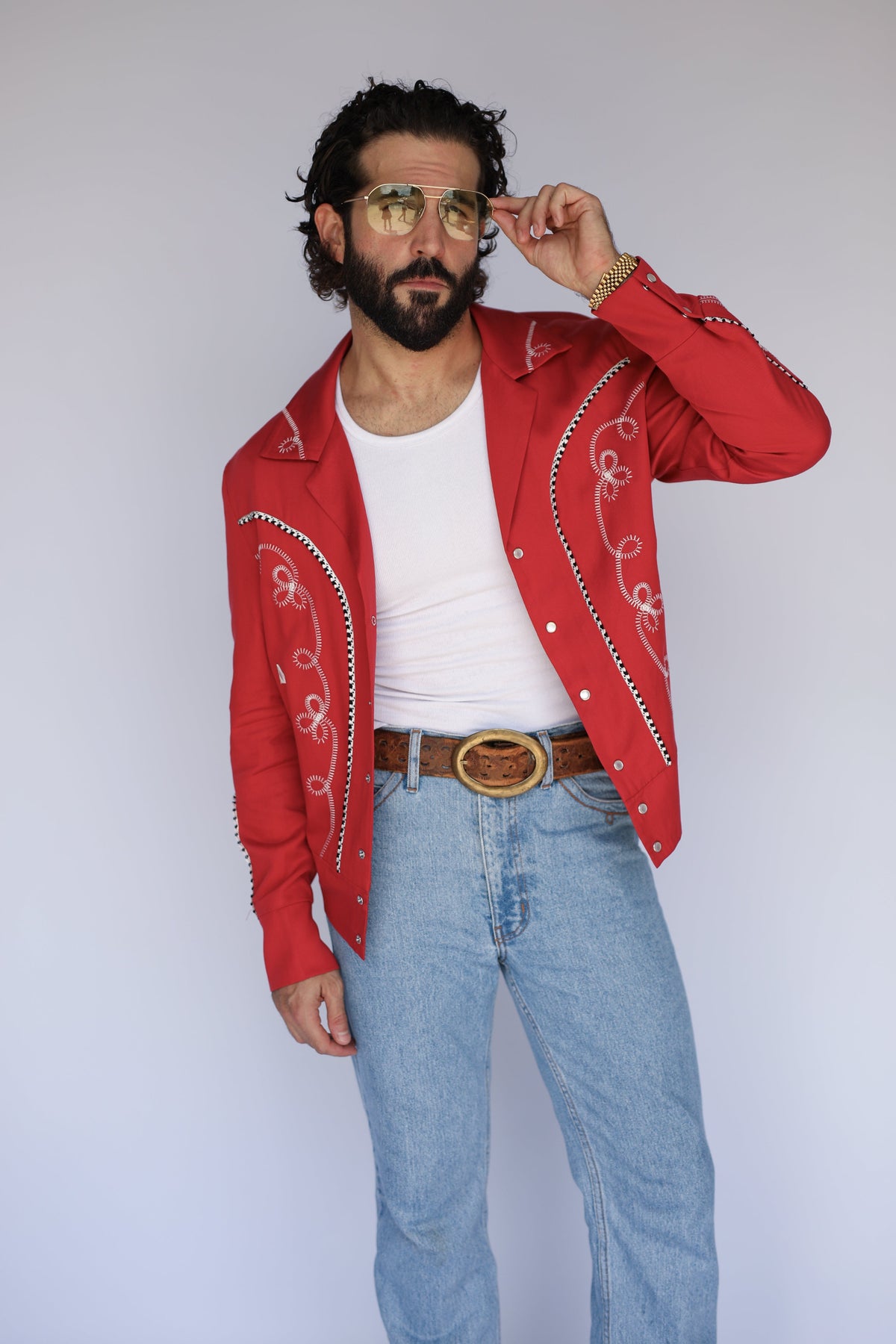 Model in the H Bar C Bolero red jacket worn open over a white tee with a brown belt and jeans.