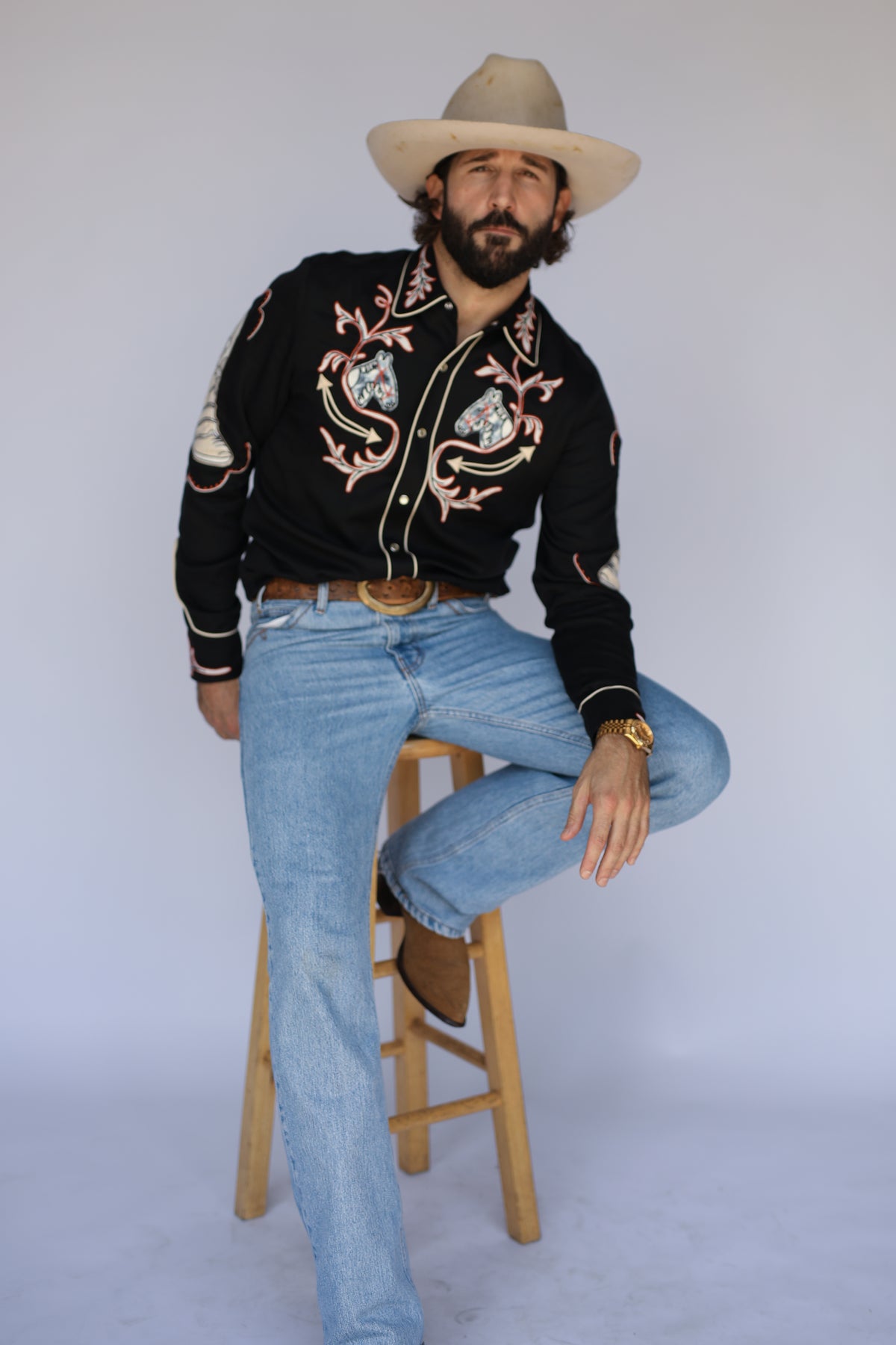 Man seated on a stool wearing the H Bar C Calabasas black chain stitch western shirt.