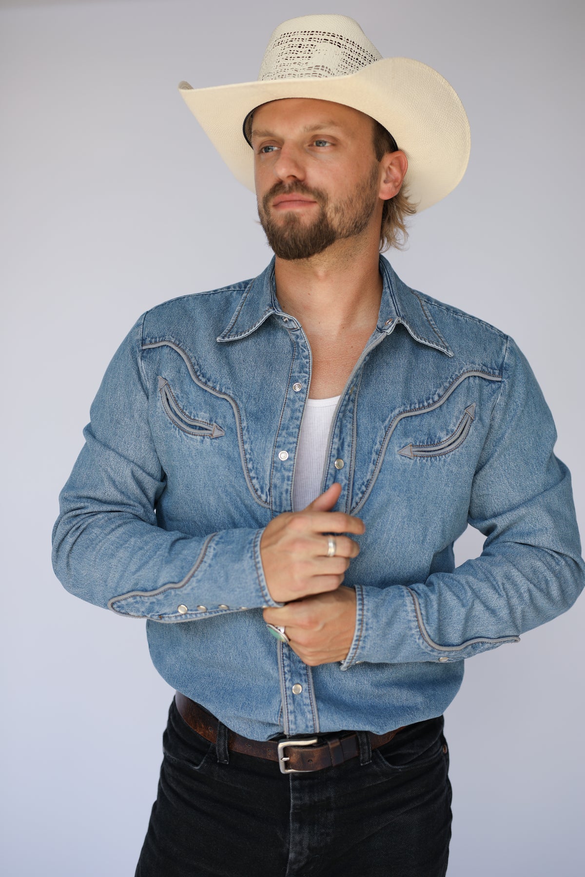 Man in a cream straw hat wearing the H Bar C San Fernando denim shirt open over a white tank.