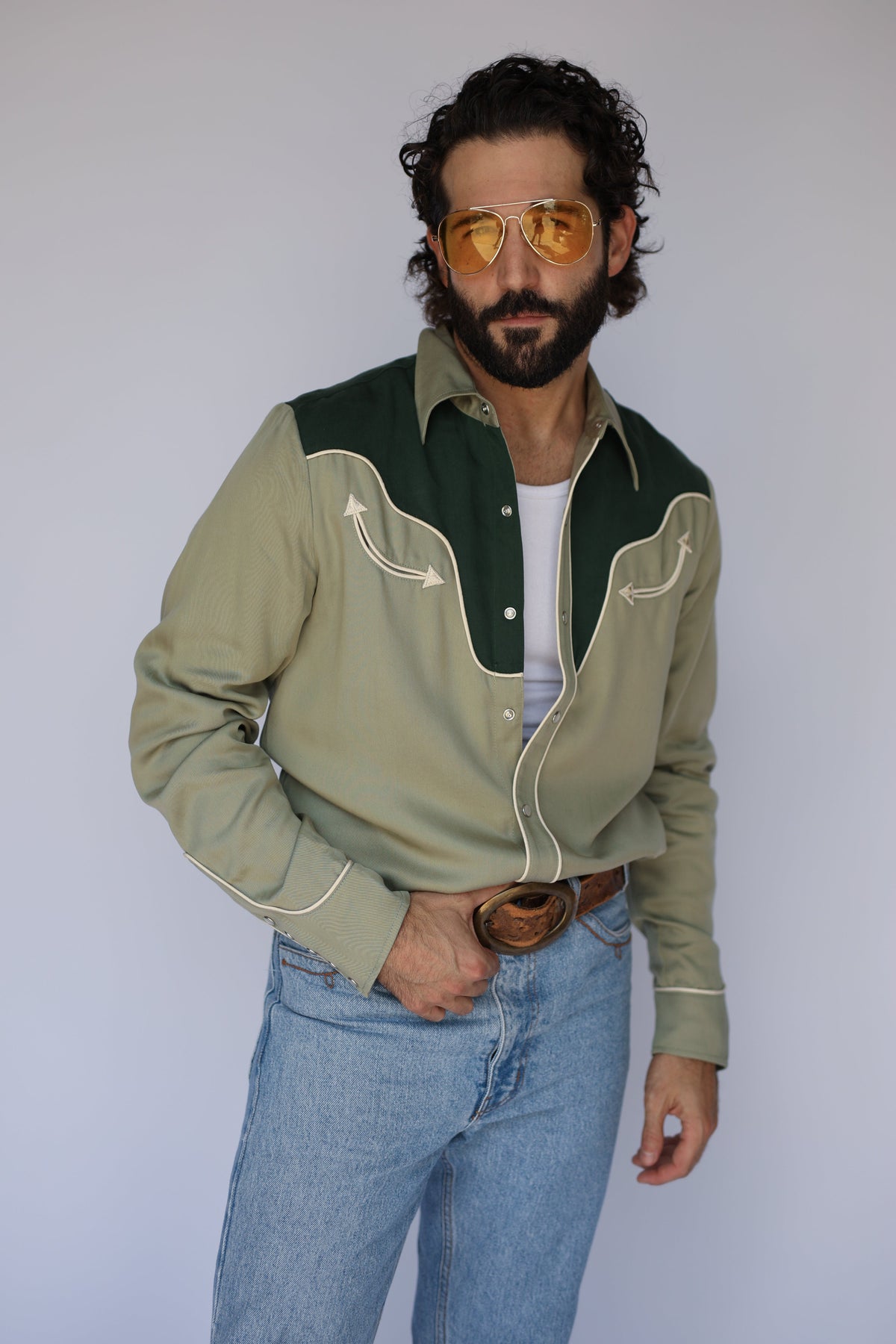 Man wearing the H Bar C San Juan men's shirt in sage green with a dark green yoke, cream piping, and arrow smile pockets, a 1940s inspired western shirt.