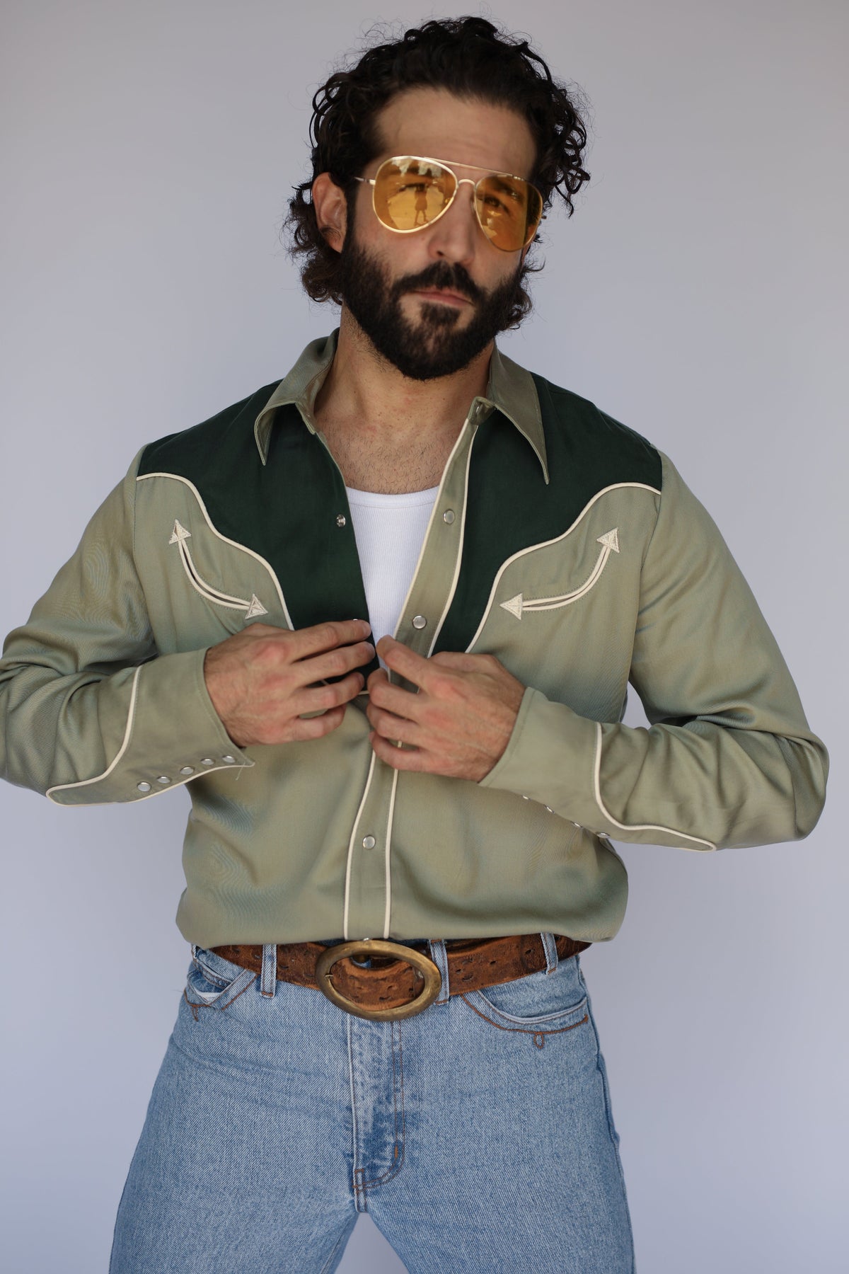 Model in the H Bar C San Juan two-tone green western shirt with contrast yoke and piping, worn with light jeans and a brown belt.