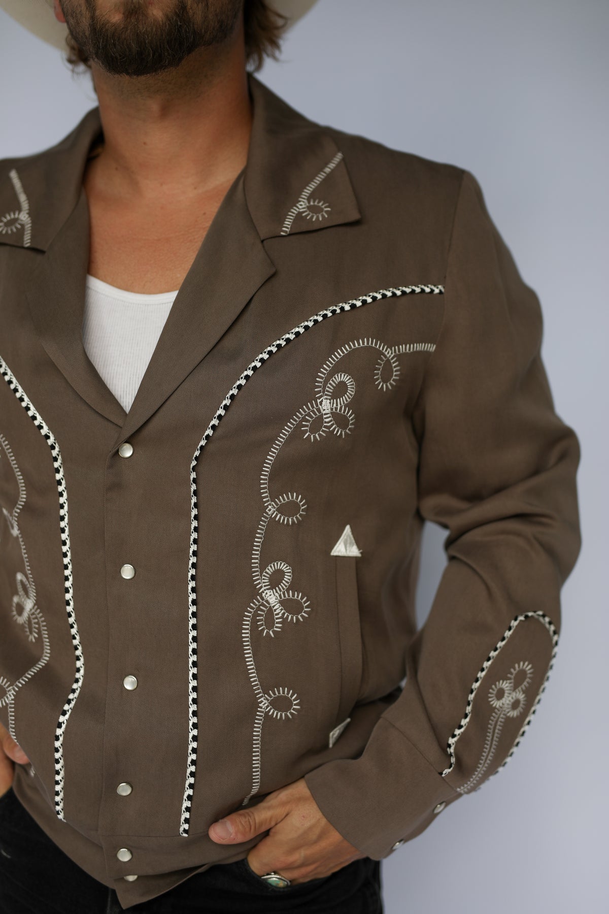 Close-up of the white chain stitch embroidery and piping on the front of the H Bar C Bolero cocoa jacket.