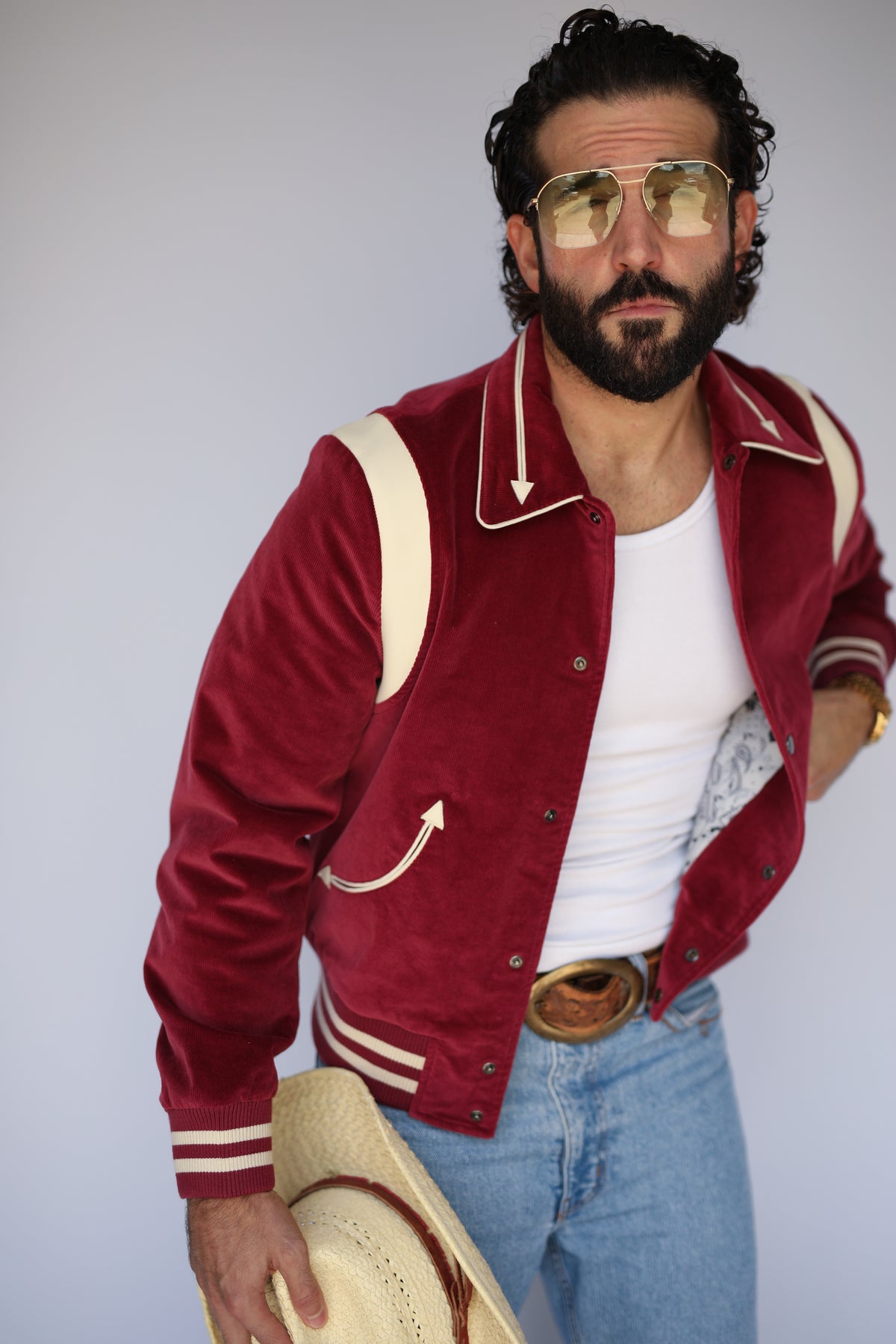 Man holding a cowboy hat wearing the H Bar C Silver Lake corduroy unisex jacket in maroon with cream lambskin shoulders.