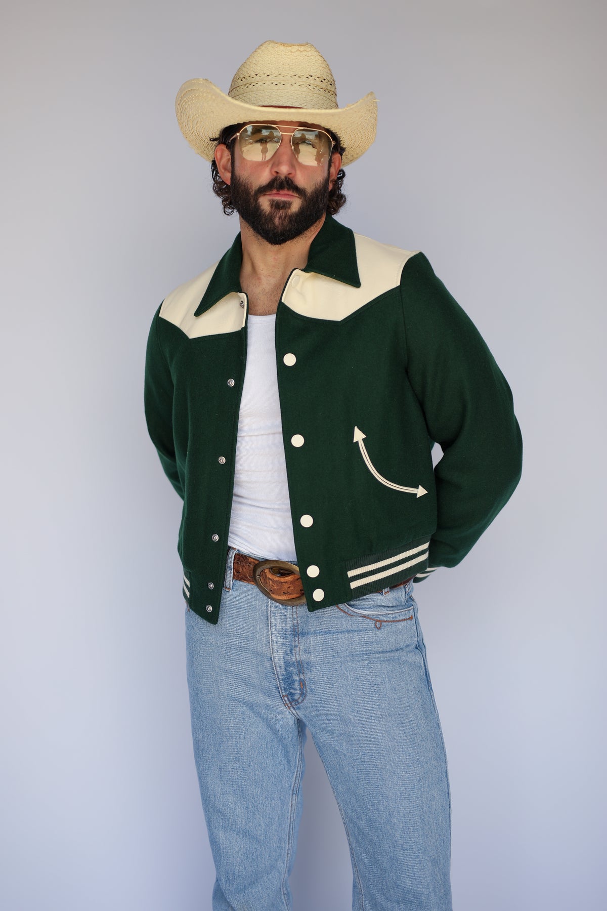 Man in a straw cowboy hat wearing The Vail unisex jacket by H Bar C in green wool with cream yoke and striped ribbing.