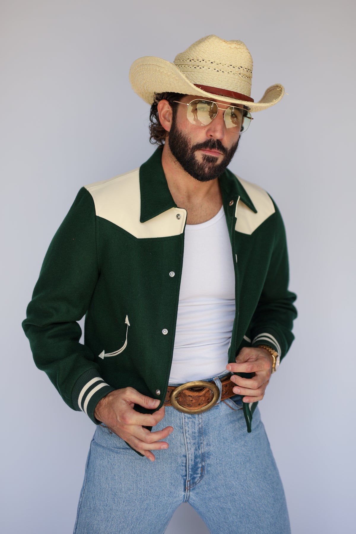 Man wearing The Vail H Bar C green and cream jacket with light jeans and a straw hat.