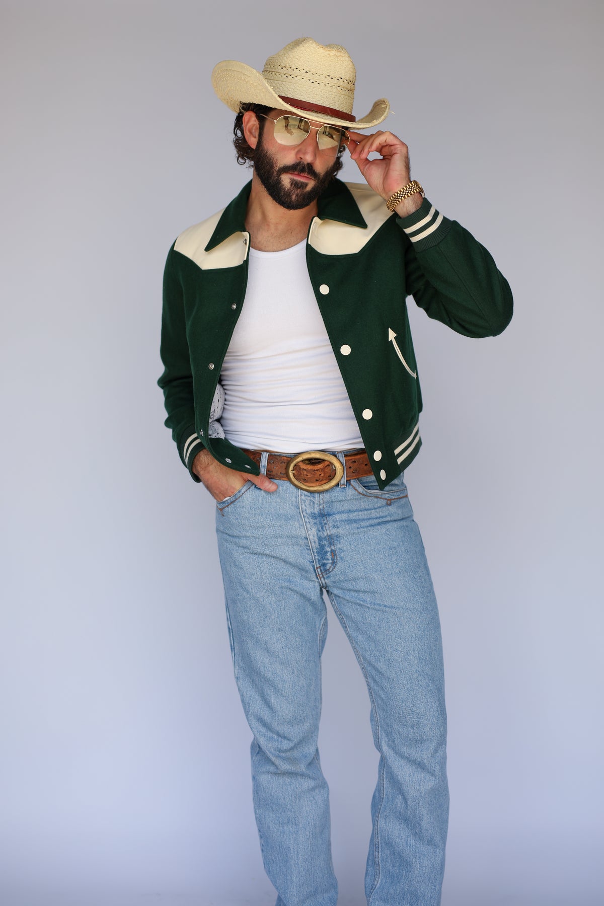 Man tipping his hat in The Vail unisex green jacket by H Bar C.