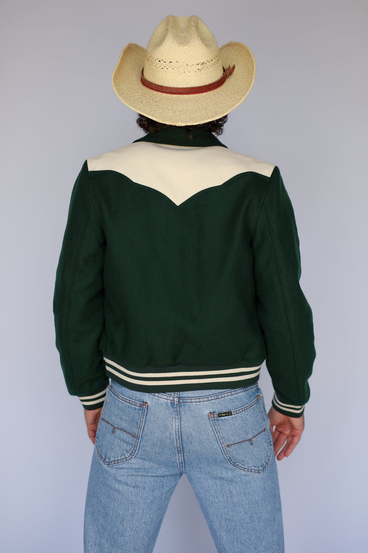 Back view of The Vail unisex green jacket by H Bar C with a straw hat.
