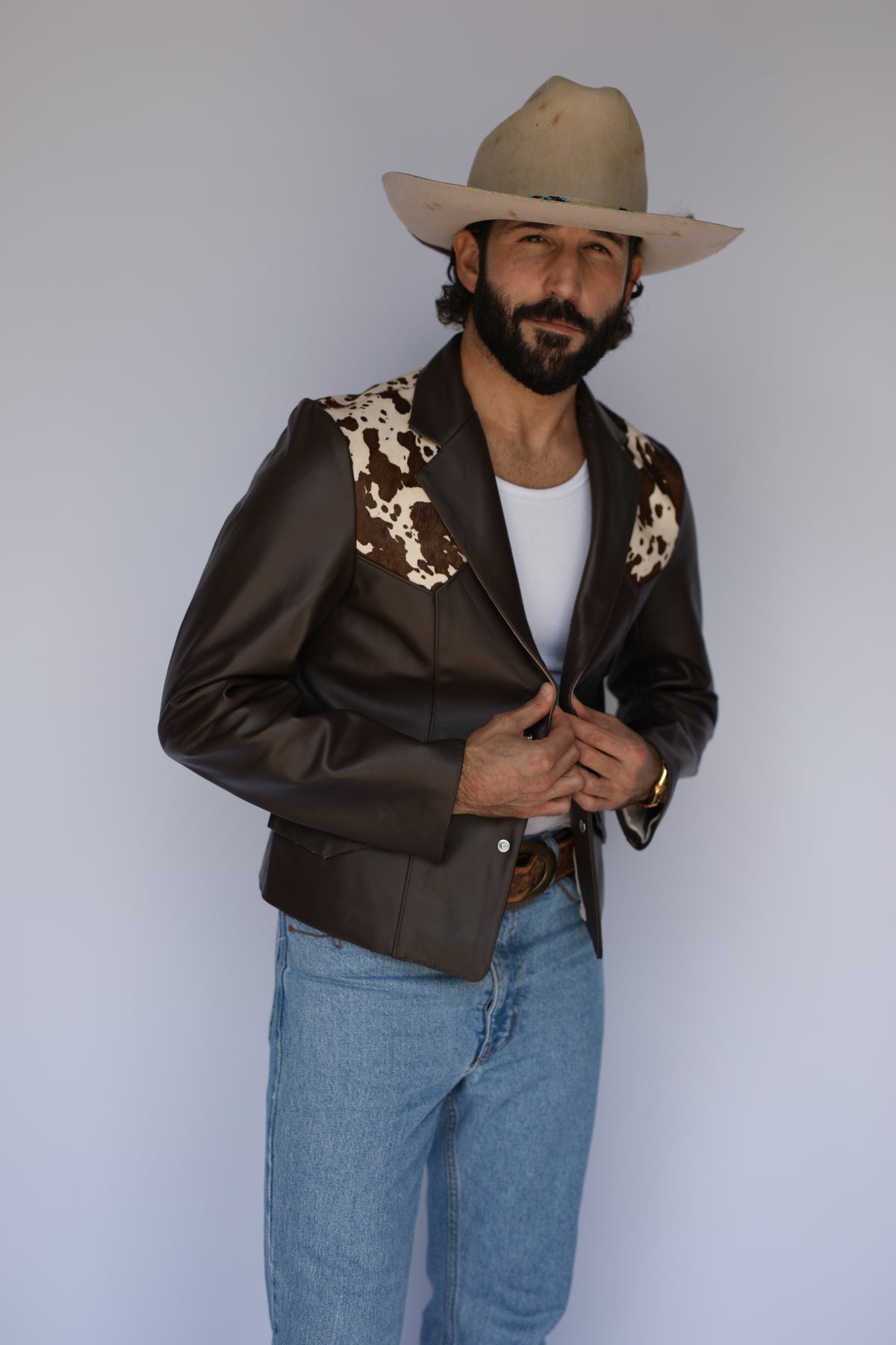 Man in a cowboy hat wearing the H Bar C Cody leather jacket in brown with a cowhide yoke, inspired by 1960s western design.