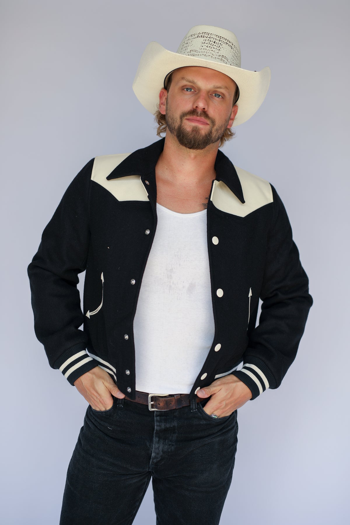 Man wearing The Vail unisex black jacket by H Bar C with arrow pockets and snap front.