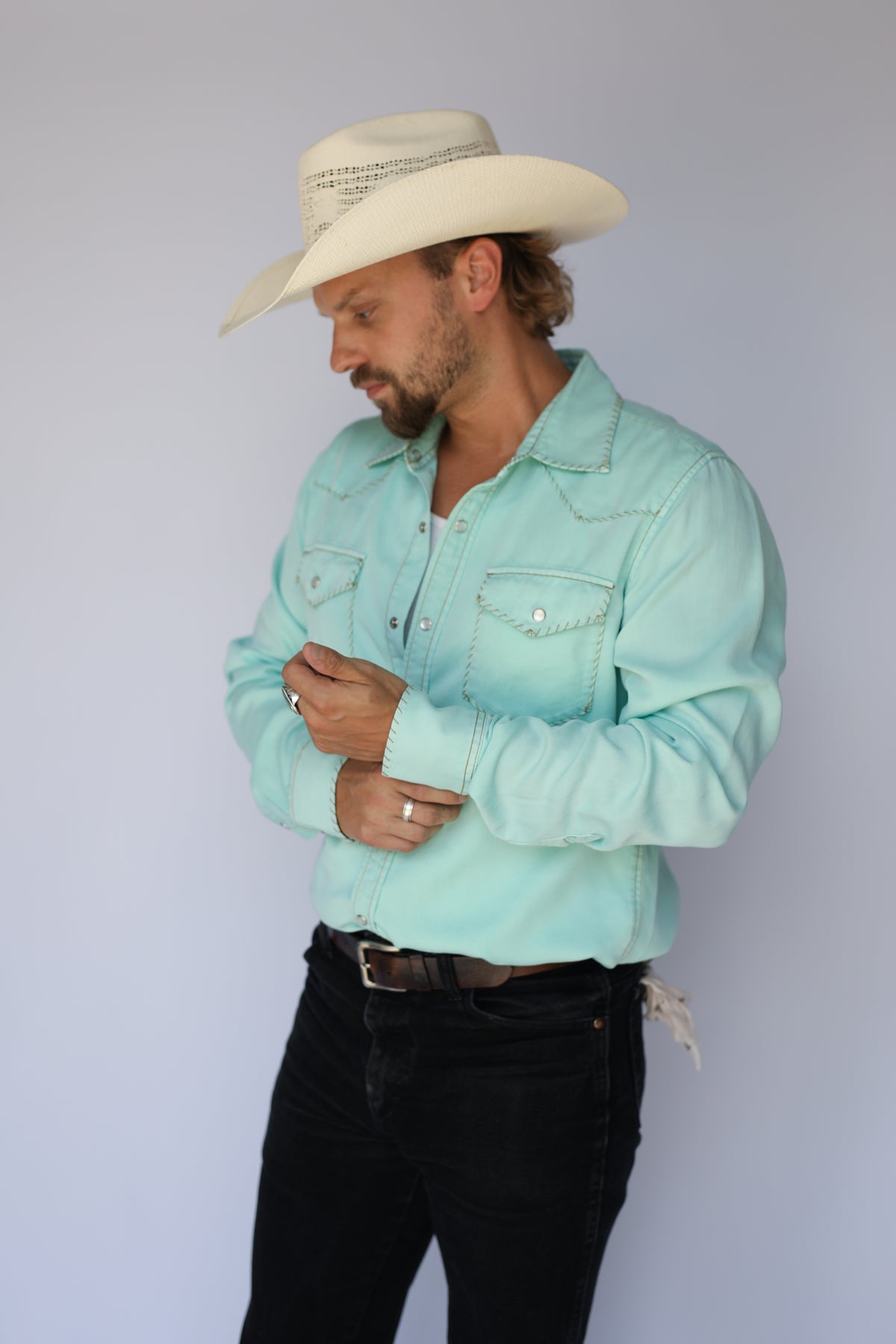 Man fastening the cuff of the H Bar C Brooklyn men's turquoise snap shirt.