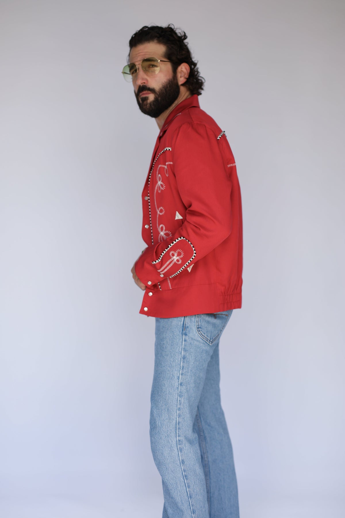 Profile view of the H Bar C Bolero men's red embroidered western jacket with light jeans.