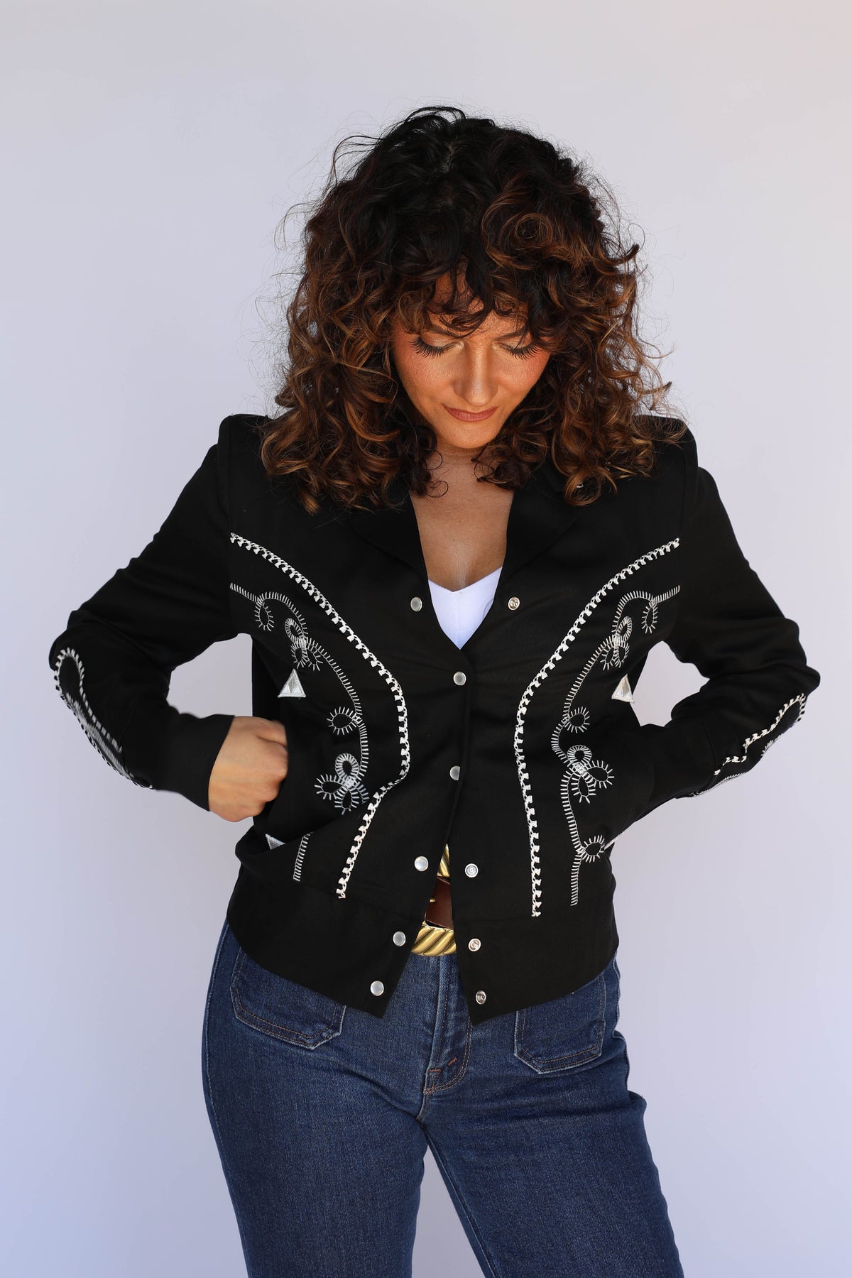 Woman holding the collar of the H Bar C Bolero women's black cropped jacket, vintage western wear.