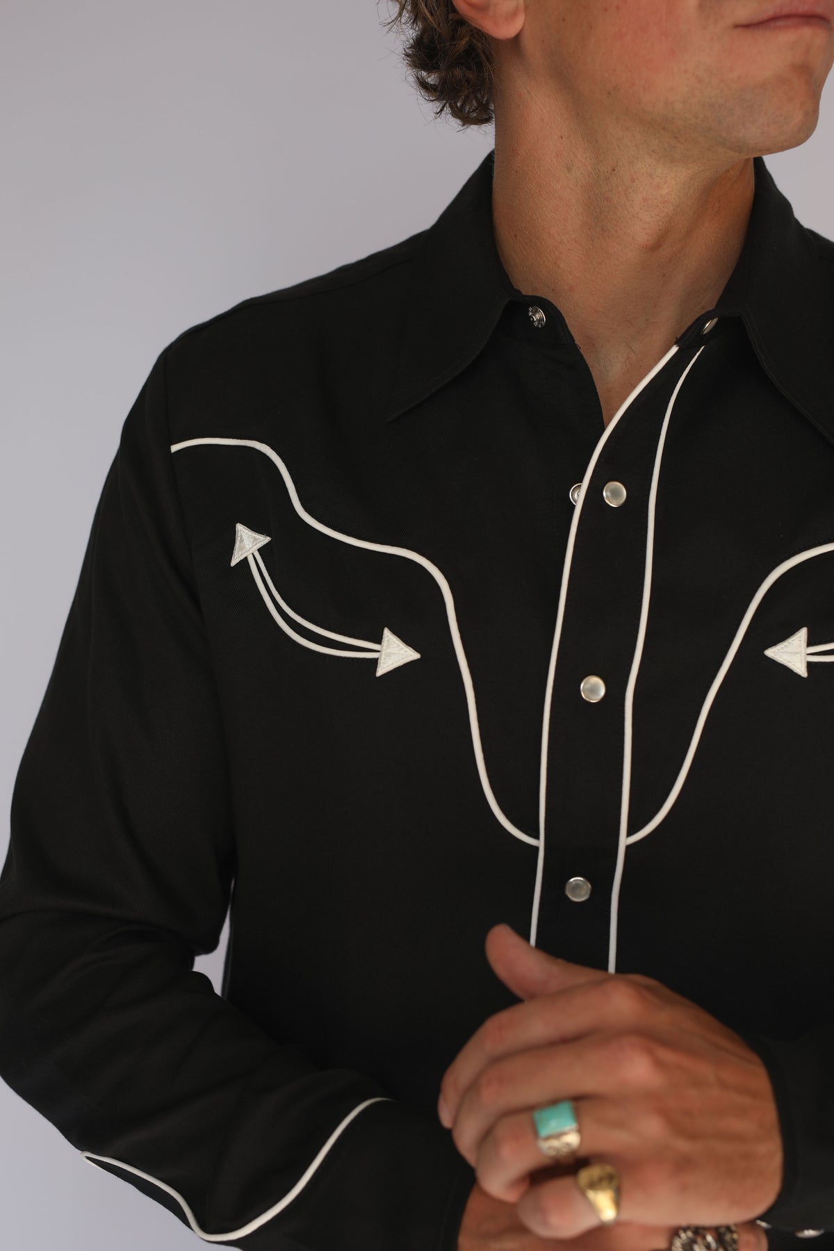 Chest detail of the H Bar C San Fernando black western shirt showing pearl snaps and white arrow embroidery, vintage inspired western wear.