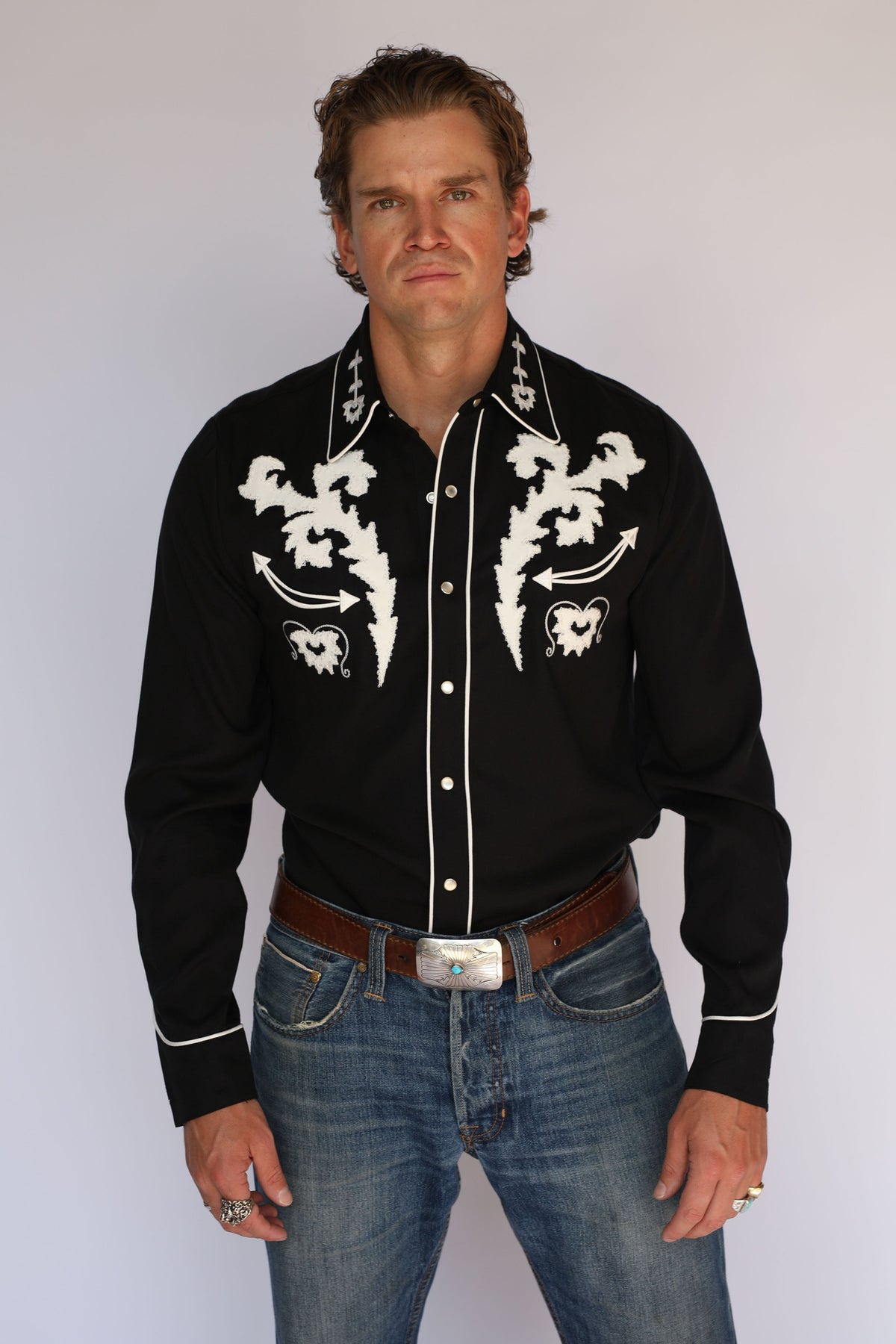 Man wearing the H Bar C Dali western shirt in black with bold white flame embroidery on the yokes, a tribute to Salvador Dalí, with jeans.