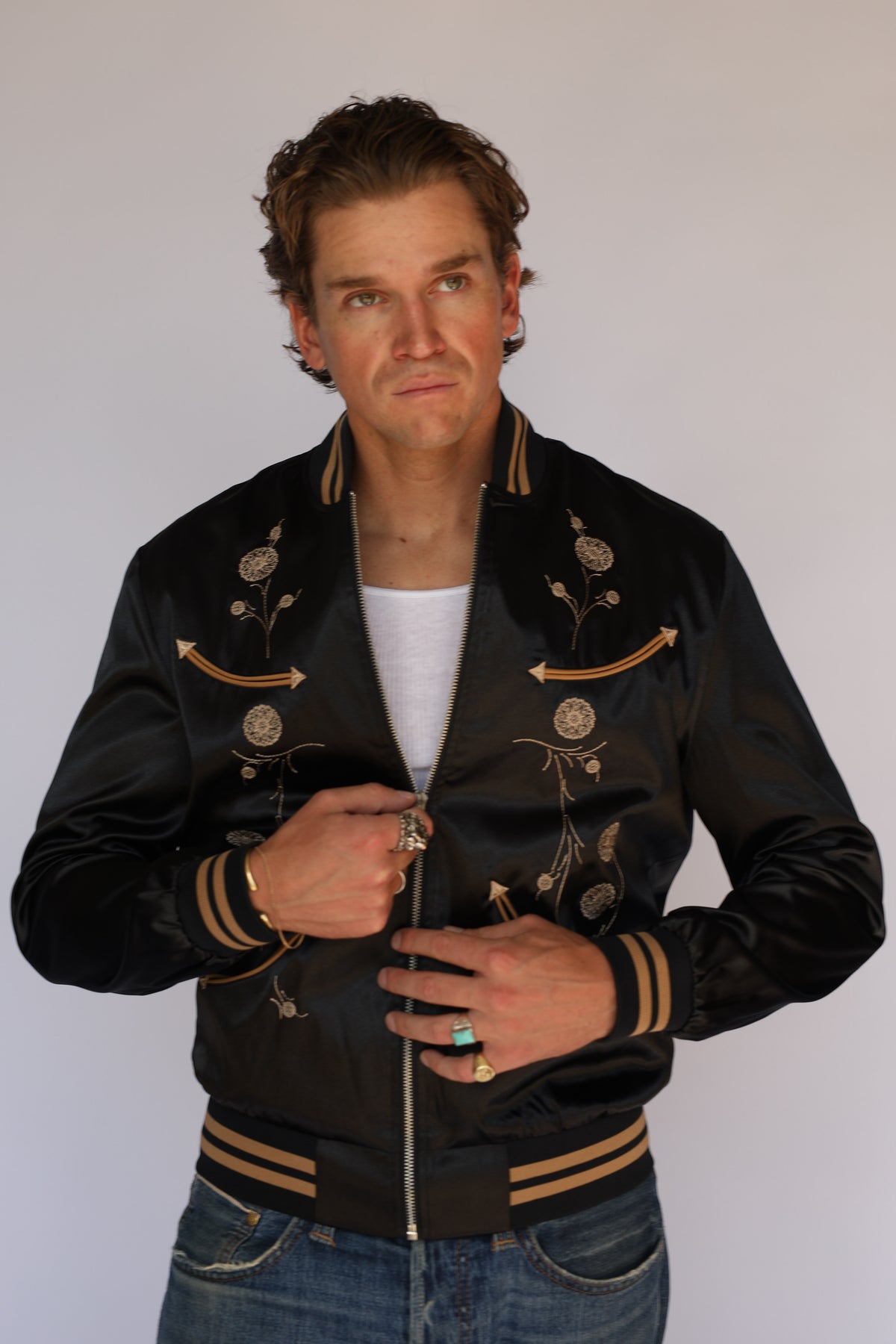 Smiling model in the H Bar C x Gibson J-200 Odessa black jacket, close-up of the embroidered front, vintage inspired western wear.