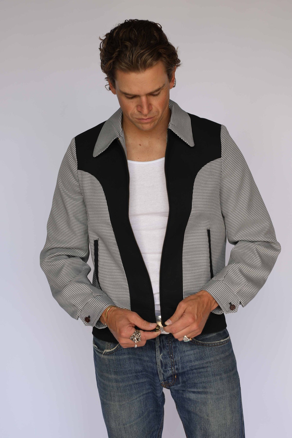 Man wearing the H Bar C Kentucky jacket in black houndstooth with black suede front panels over a white tank.